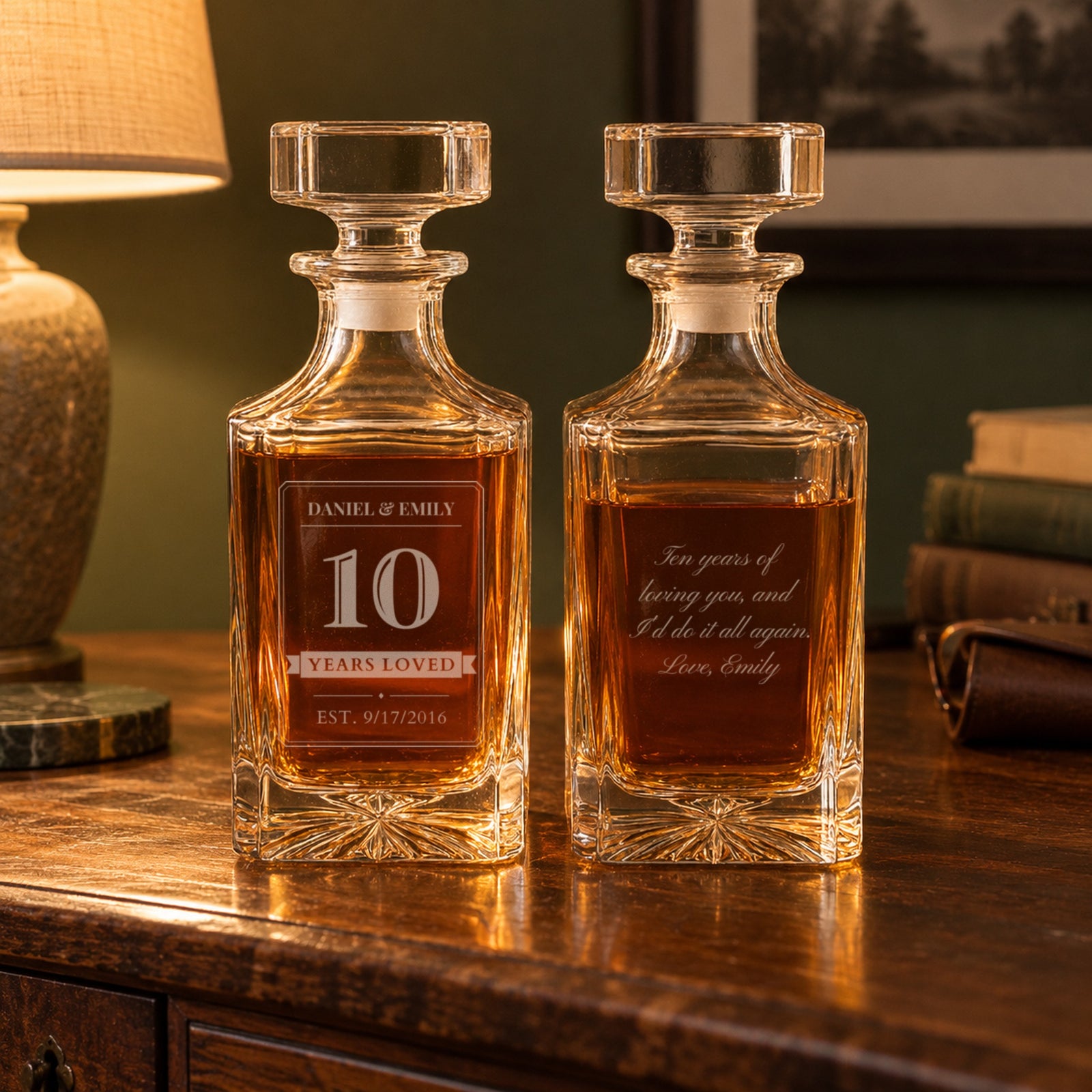 Two engraved 10 year anniversary decanters for him on a walnut sideboard, front reading Daniel and Emily, 10, Years Loved, EST. 9/17/2016, back with a love note