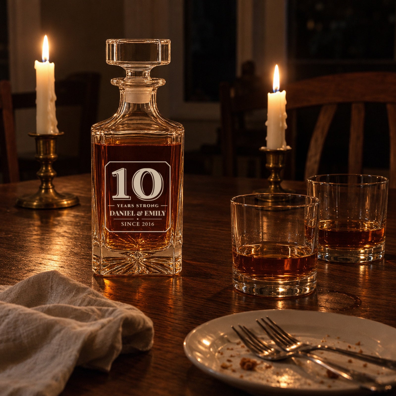 Personalized decanter engraved 10 Years Strong, Daniel & Emily, on a candlelit dinner table with two glasses, a 10th anniversary gift for him