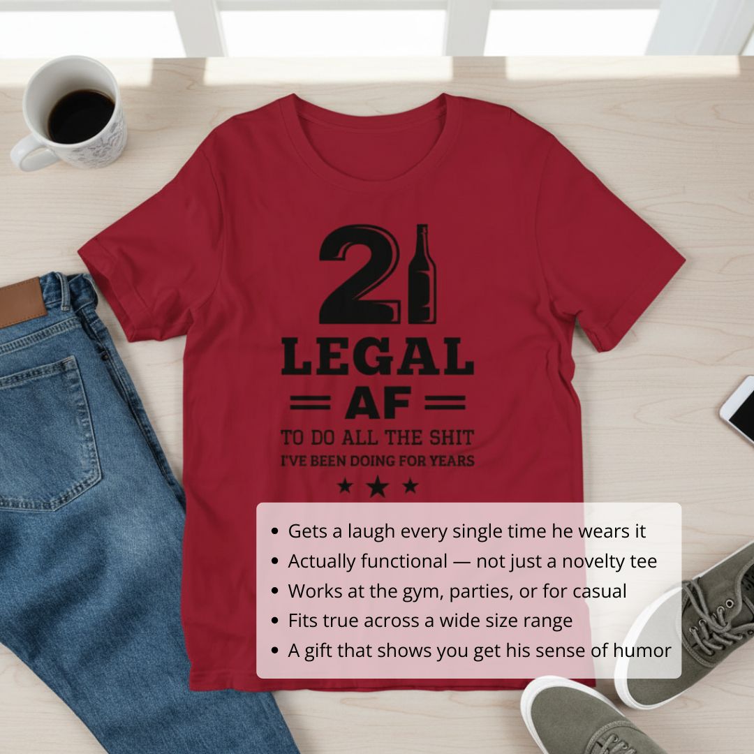 Red t-shirt with black printed text reading "21 LEGAL AF TO DO ALL THE SHIT I'VE BEEN DOING FOR YEARS" and decorative stars, displayed flat lay with coffee mug and jeans