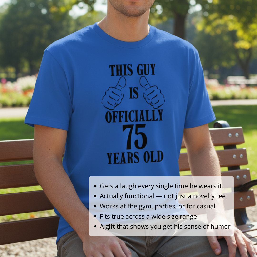 Man wearing royal blue t-shirt with black text reading "This Guy is Officially 75 Years Old" and dual thumbs-up graphic, seated outdoors on park bench