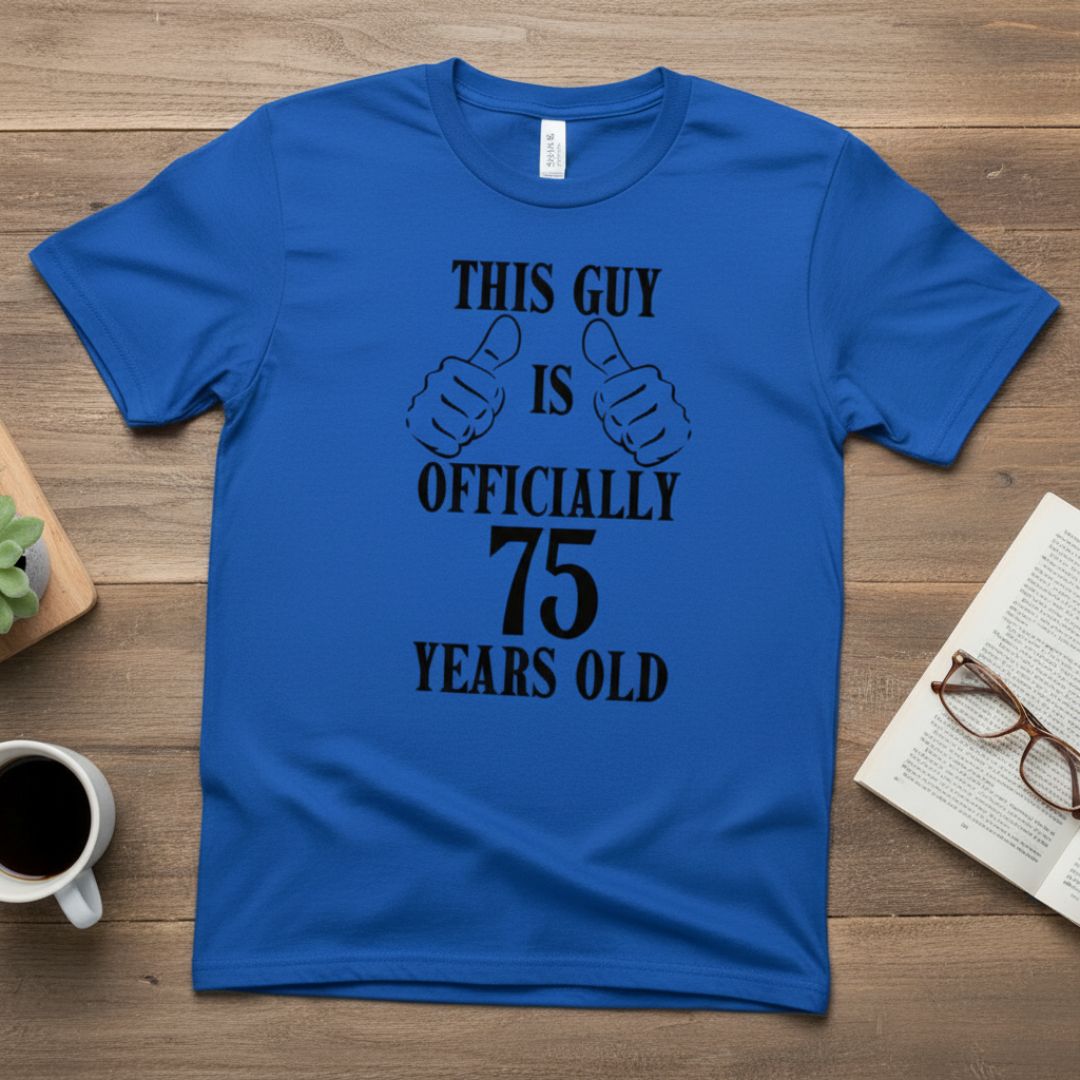 Royal blue t-shirt with black printed design reading "This Guy is Officially 75 Years Old" flanked by two thumbs-up illustrations