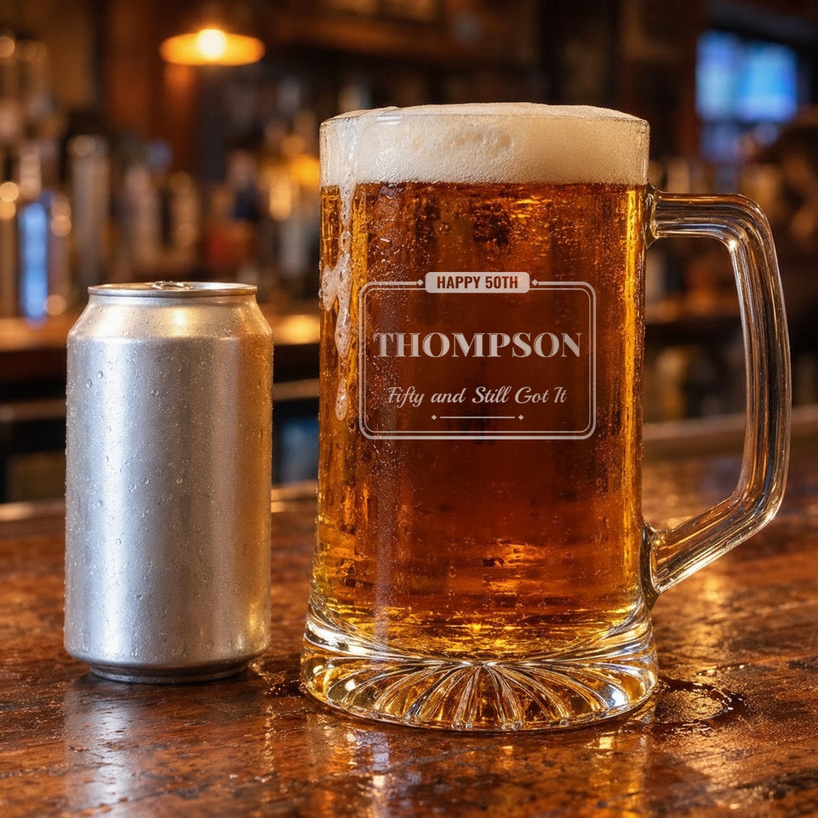 25 oz personalized birthday beer stein beside a 12 oz beer can on a bar, engraved Happy 50th, Thompson and Fifty and Still Got It