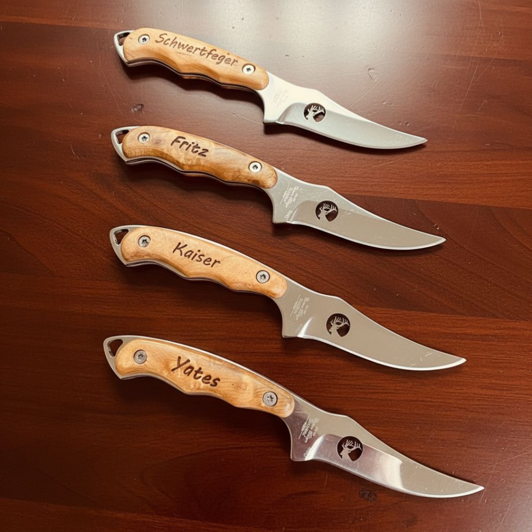 Four fixed-blade hunting knives with wooden handles, each personalized with sample names Schwertfeger, Fritz, Kaiser, and Yates engraved on the scales, displayed on a wood surface.