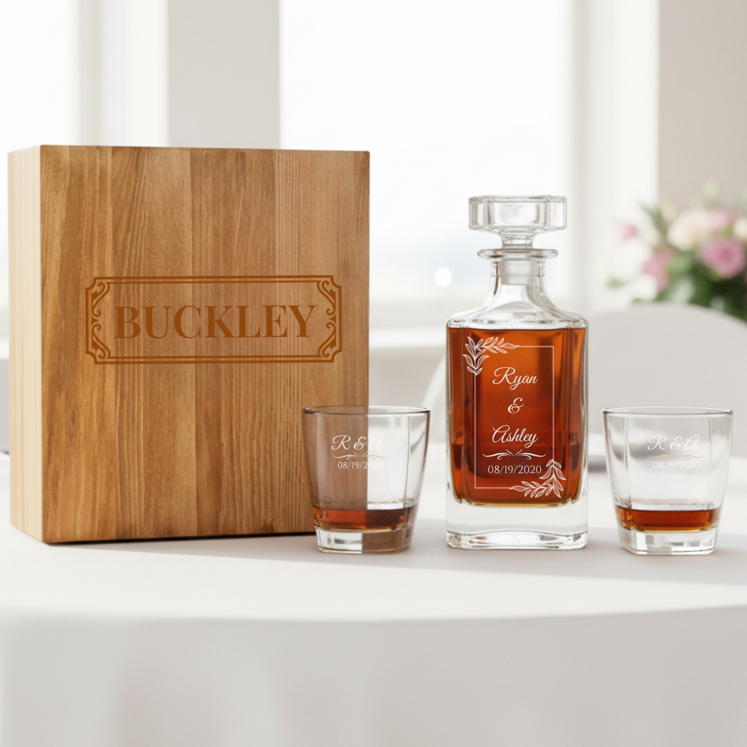 Handcrafted wooden 7 year anniversary decanter box engraved on the front with the family name, displayed beside the crystal decanter and a poured whiskey glass.
