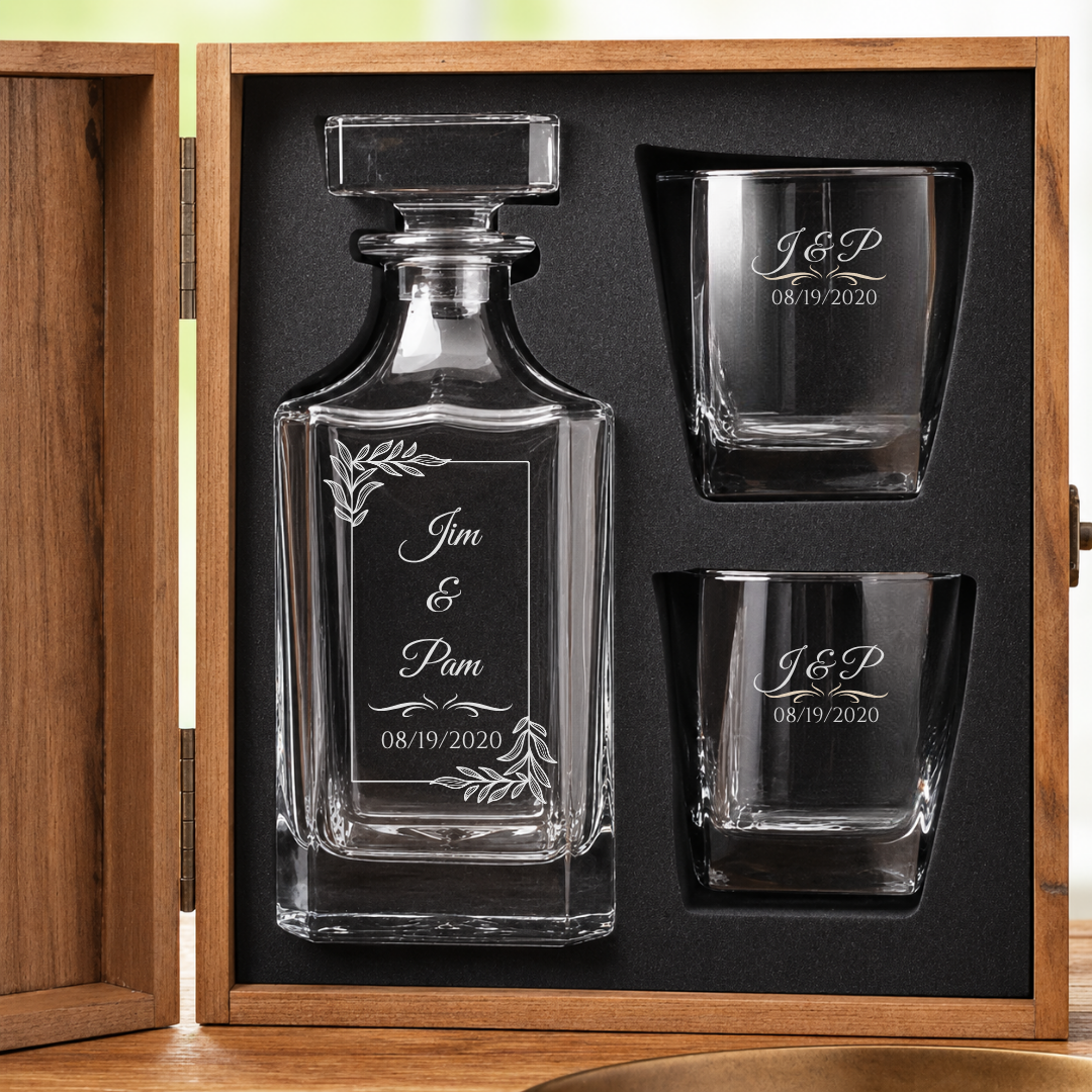 Open wooden gift box holding the 7 year anniversary decanter and two matching whiskey glasses, each engraved with the couple's names and anniversary date.