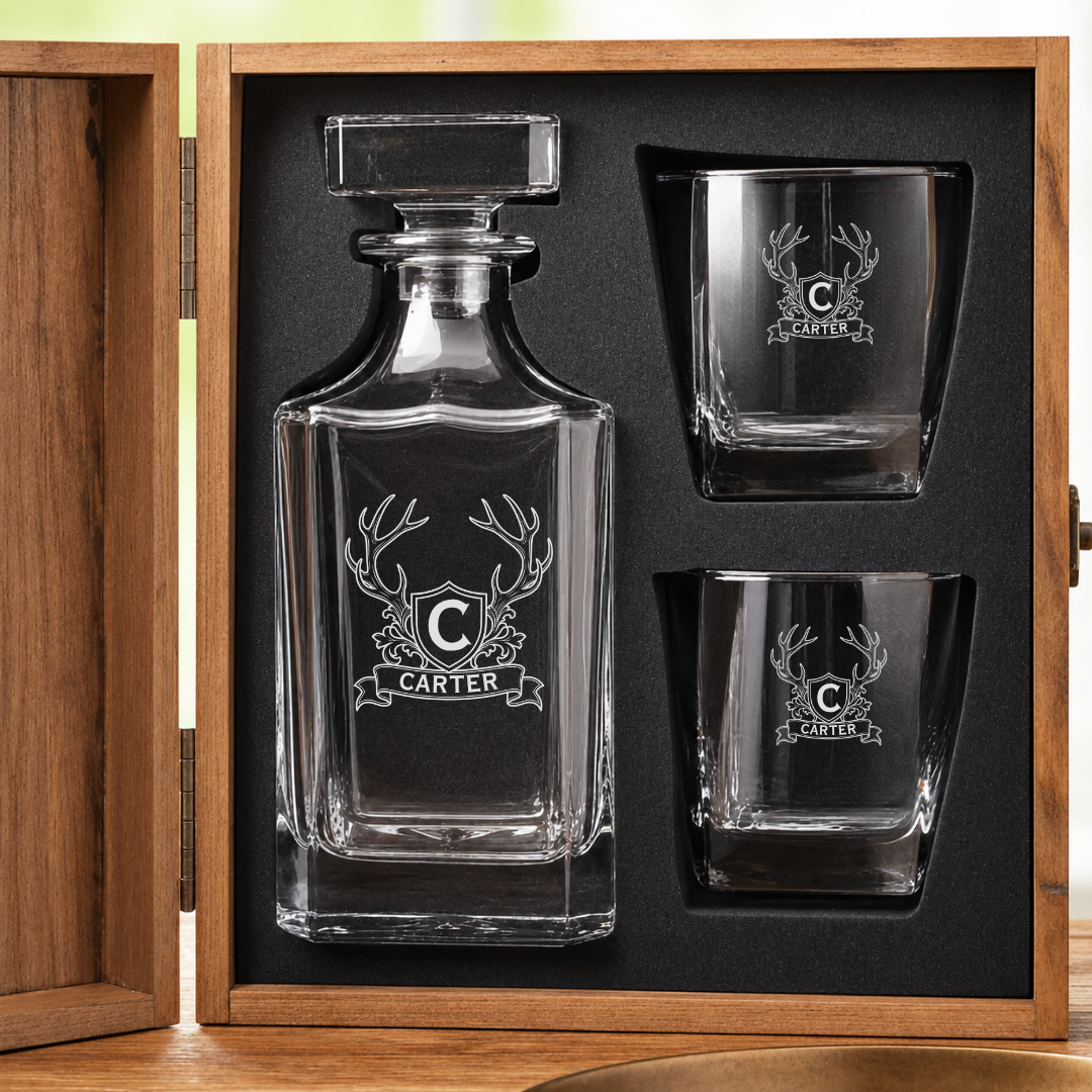 Custom whiskey decanter and two rocks glasses engraved with an antler crest and family name, set in the foam-lined wooden gift box