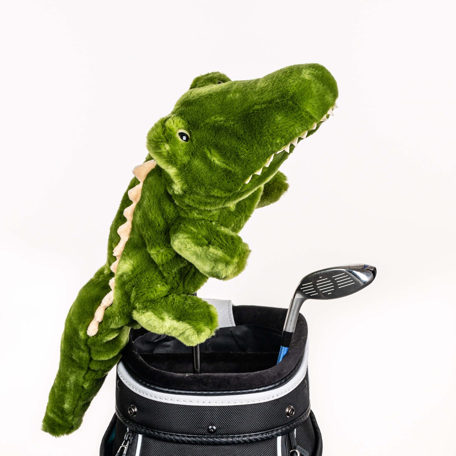 Plush green alligator golf headcover covering a driver in a black golf bag, a standout golf gift for men from Groovy Guy Gifts