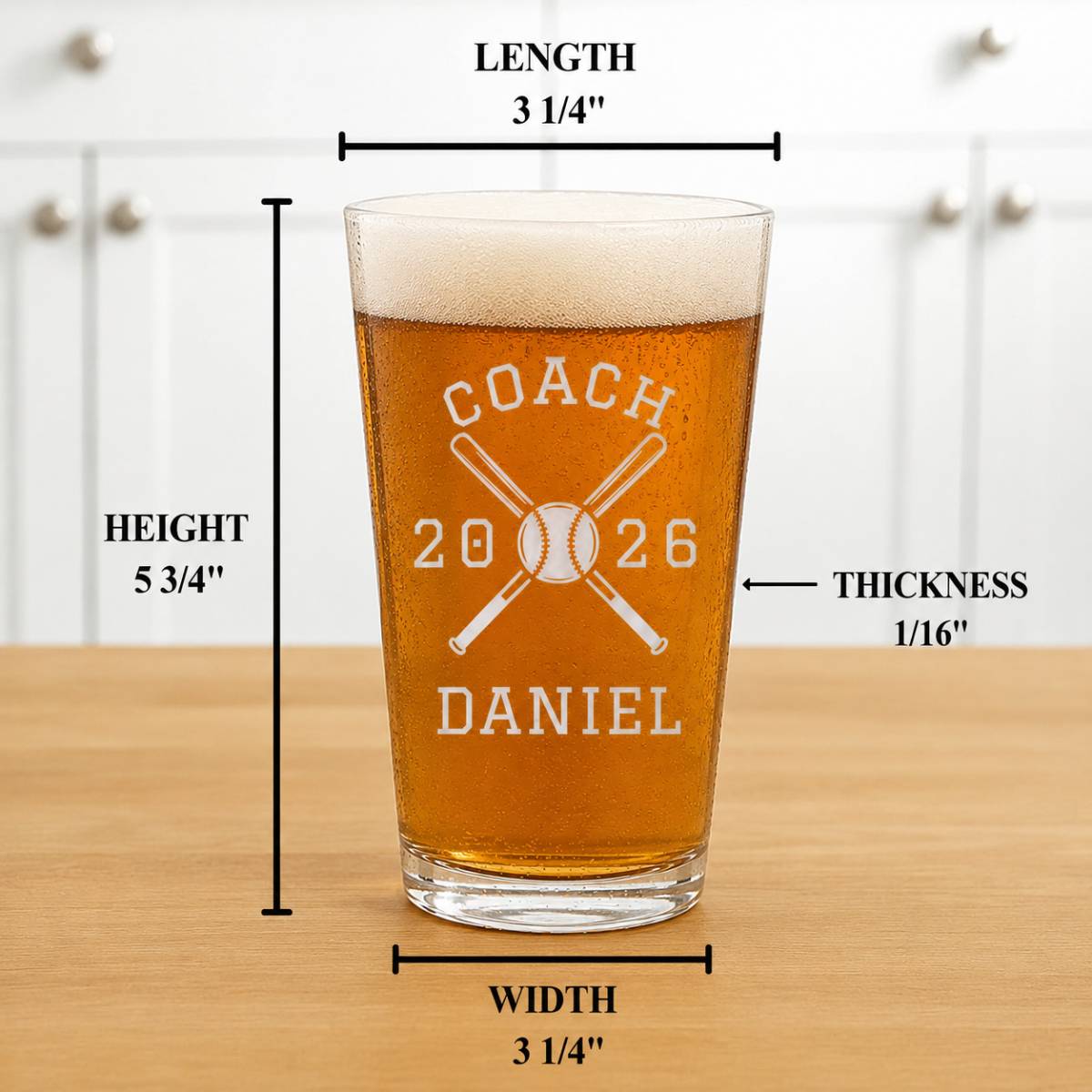 Engraved pint glass with sample personalization reading "COACH 2026 DANIEL" and crossed baseball bats, showing dimensions of 5 3/4" height and 3 1/4" width