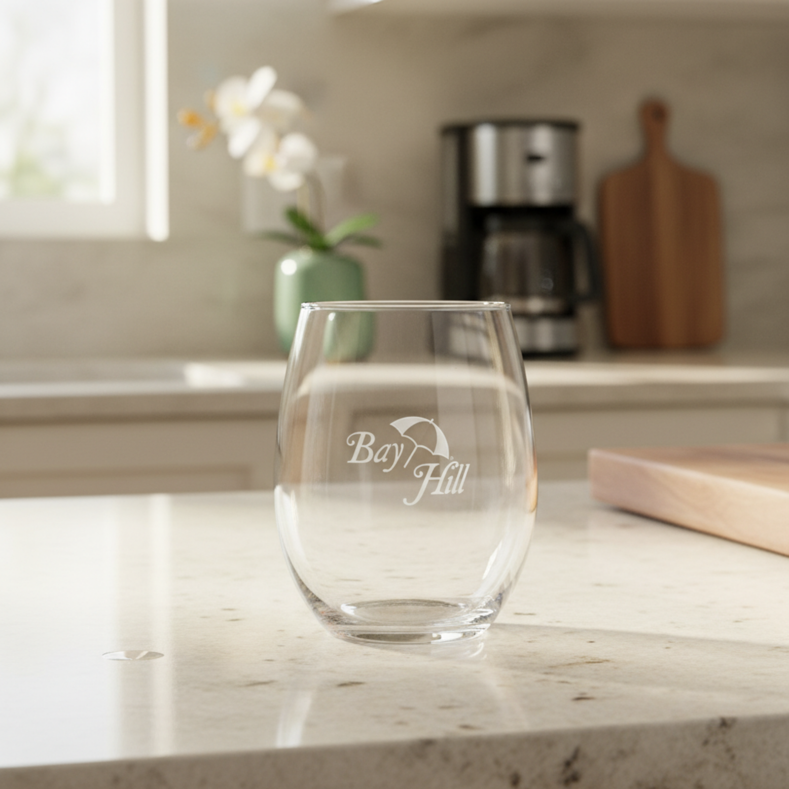 Engraved stemless wine glass with a sample logo, shown on a kitchen counter as a branded corporate gift.