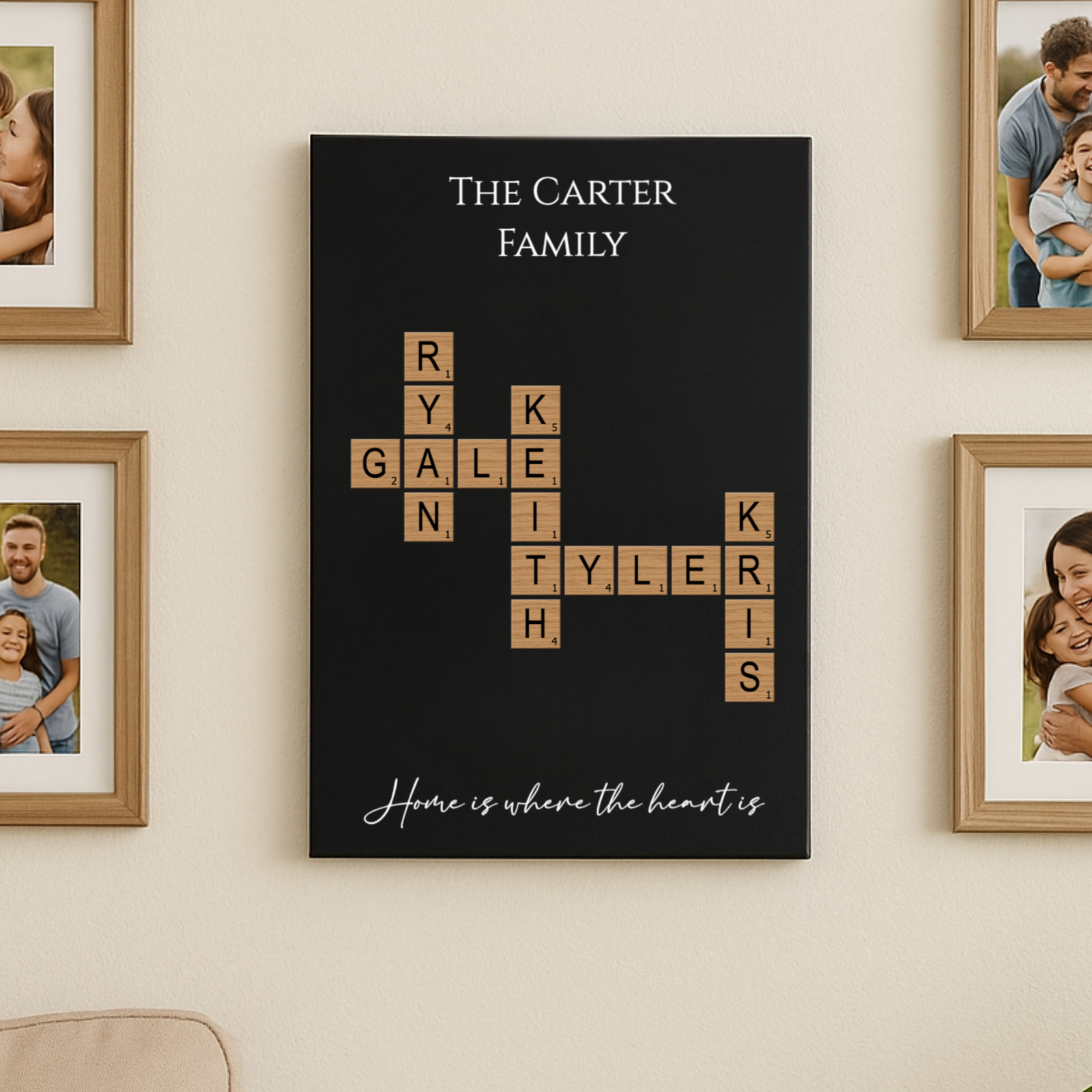 Black wall sign with sample family name "Carter" at top, family members' names arranged in crossword puzzle format using wood-grain tiles, "Home is where the heart is" script at bottom, displayed among framed family photos