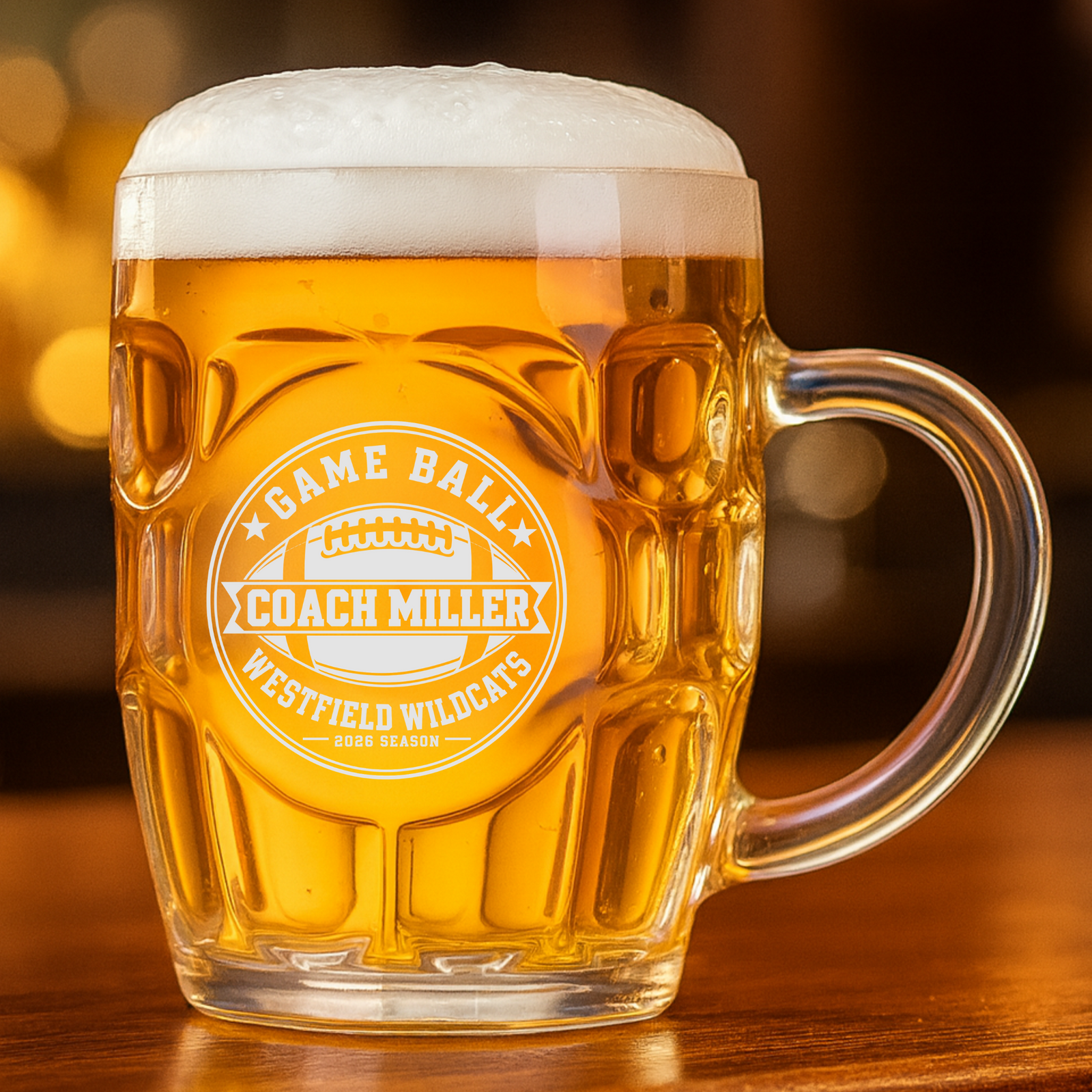 Personalized football beer stein filled with lager, engraved with a Game Ball crest reading Coach Miller, Westfield Wildcats, 2026 Season