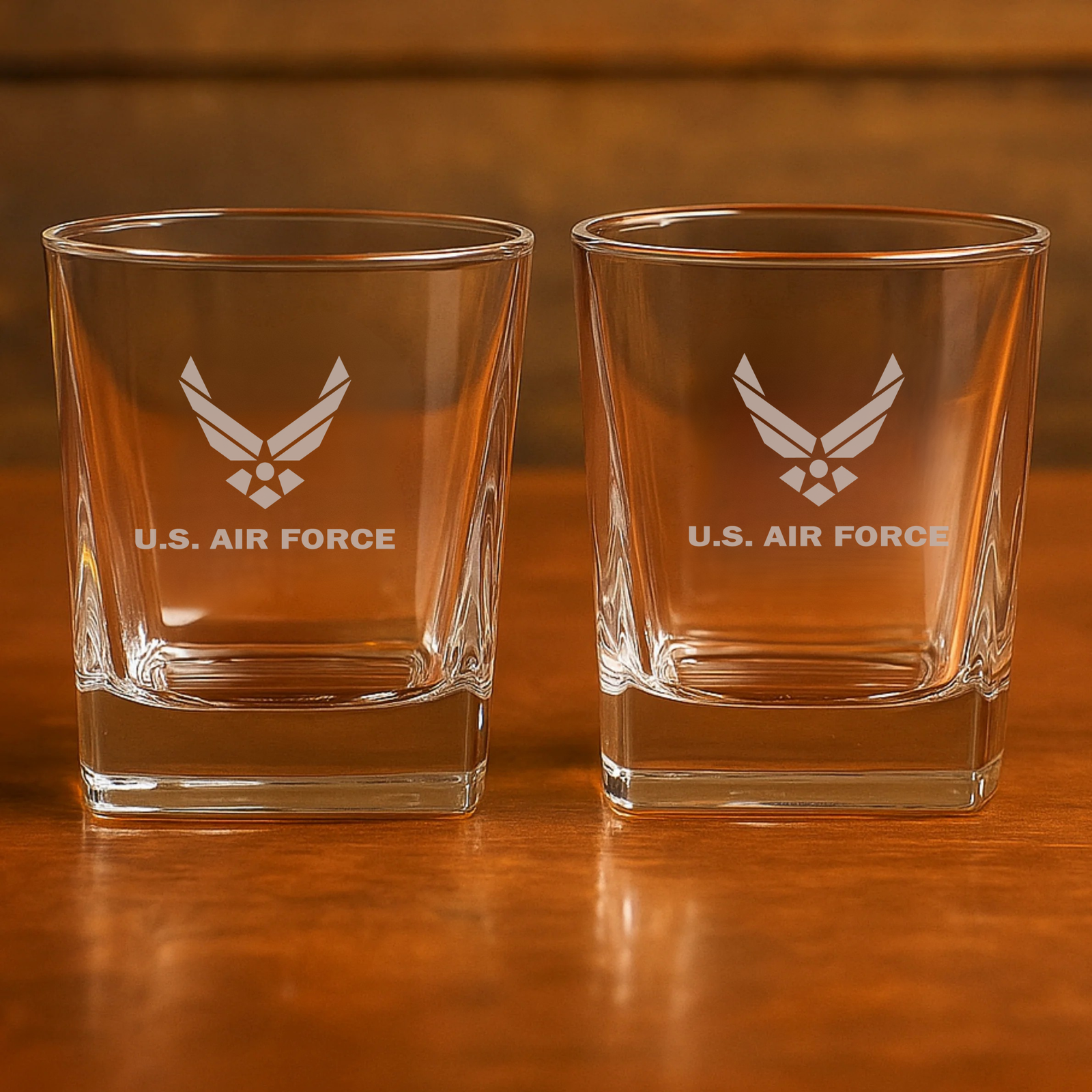 Pair of whiskey glasses engraved with U.S. Air Force winged insignia, displayed on wooden surface