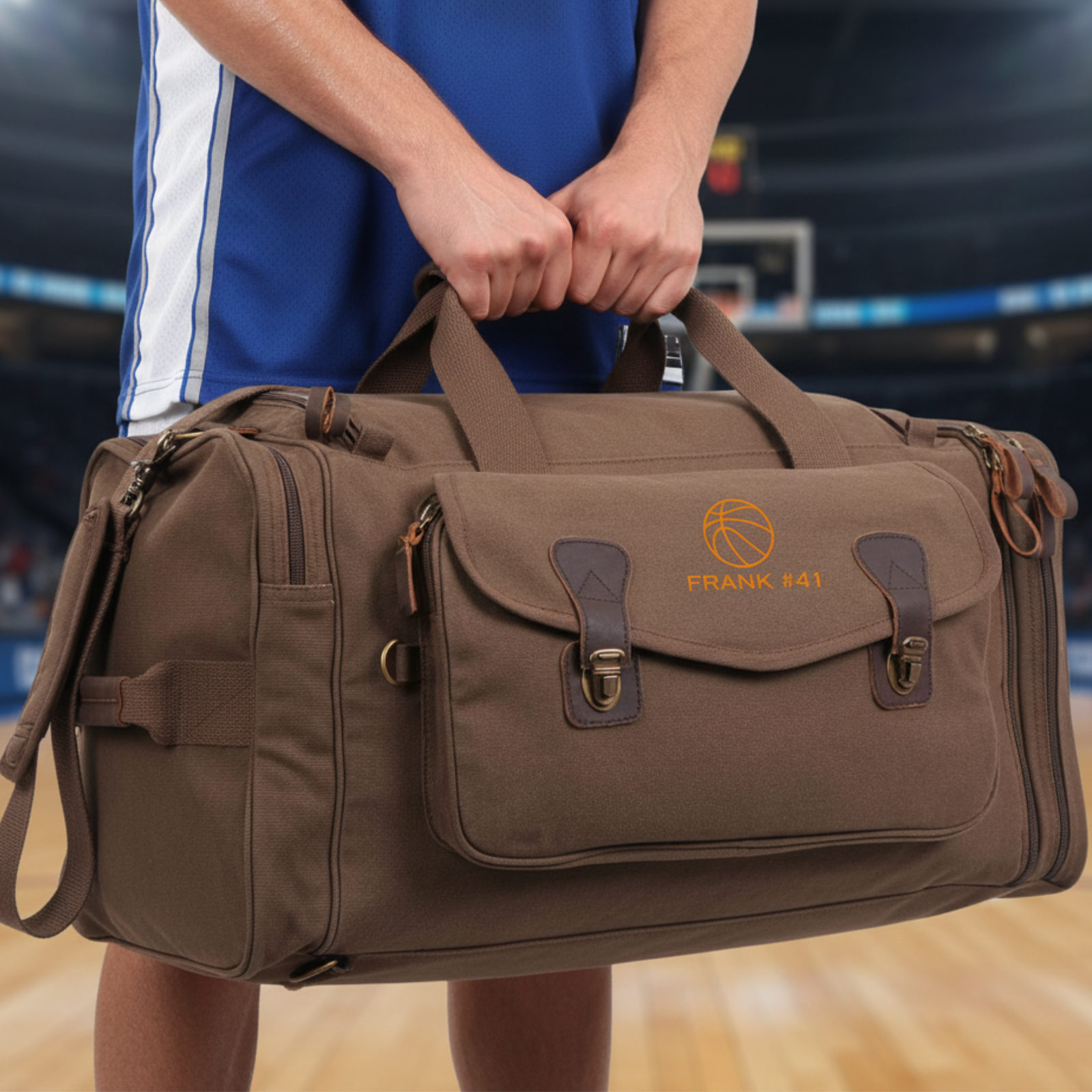 Brown canvas duffle bag with leather handles and brass hardware, personalized with sample text "FRANK #41" and basketball icon in gold lettering