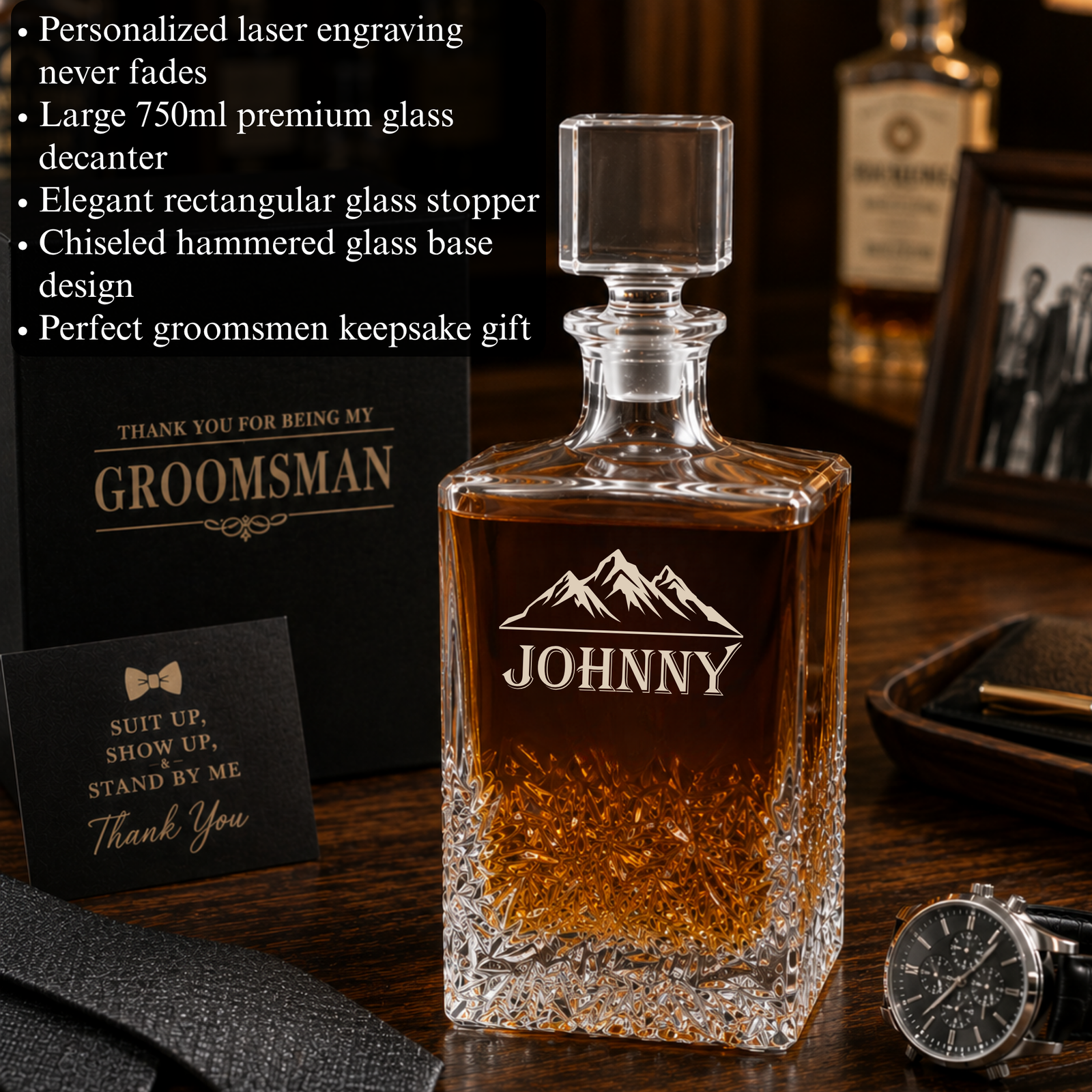 Engraved whiskey decanter with sample name "Johnny" and mountain design, displayed with groomsman gift cards and accessories on wood surface