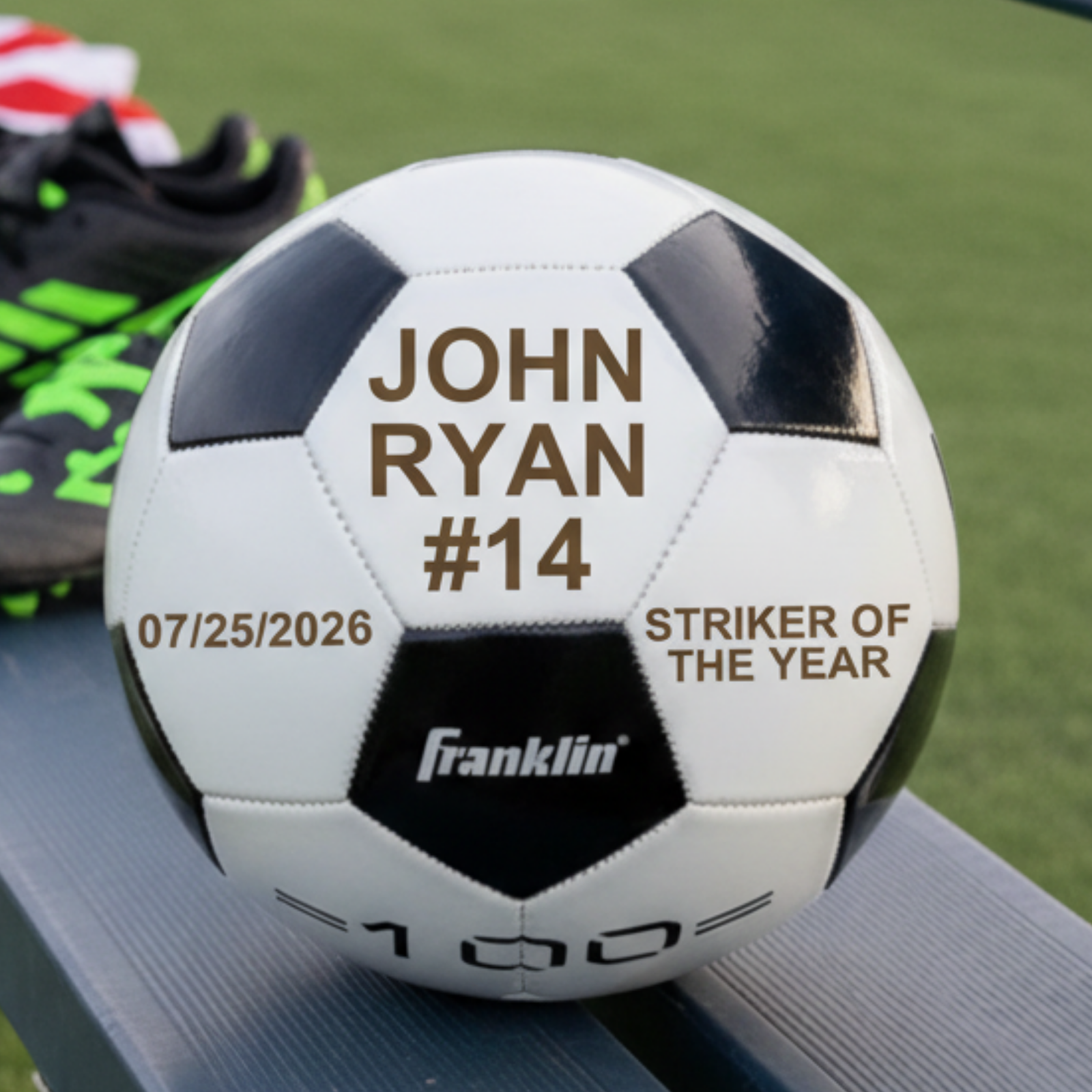 Soccer ball with sample personalization reading "JOHN RYAN #14", date "07/25/2026", and "STRIKER OF THE YEAR" engraved across white and black panels
