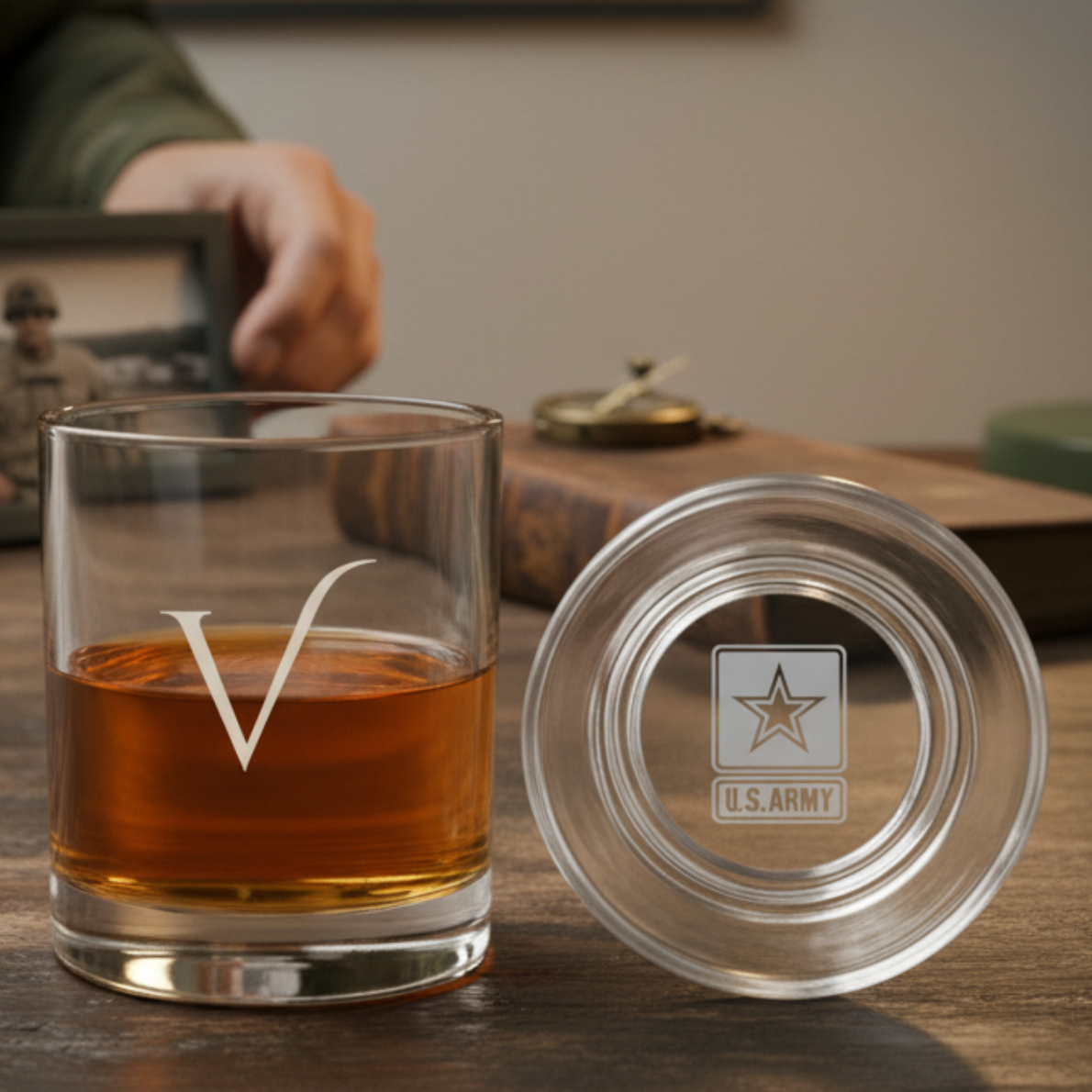 Engraved whiskey glass with sample U.S. Army insignia on bottom, filled with amber liquid, displayed with matching lid on wooden surface