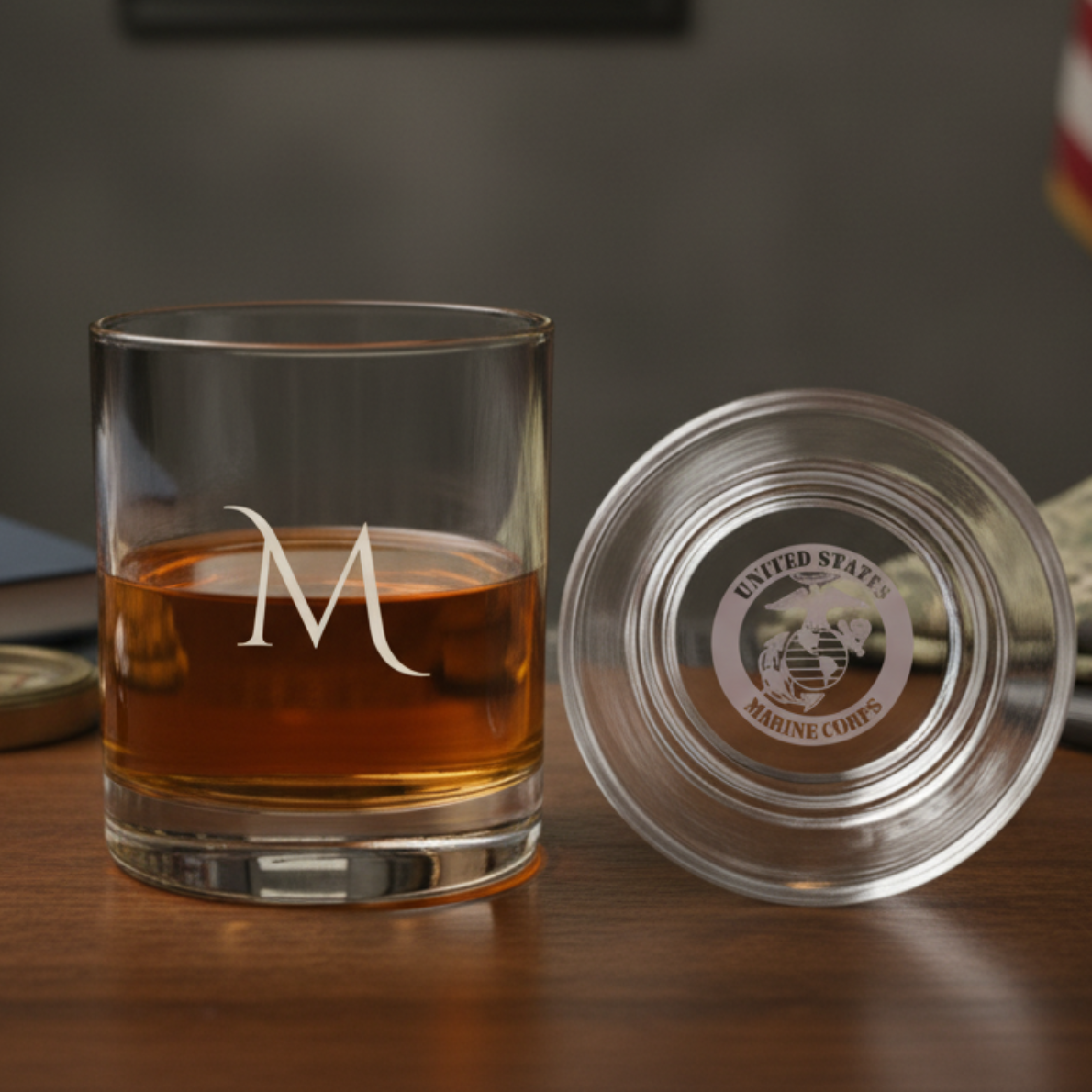 Engraved whiskey glass with sample initial "M" filled with amber liquid, shown with matching glass lid engraved with United States Marine Corps emblem