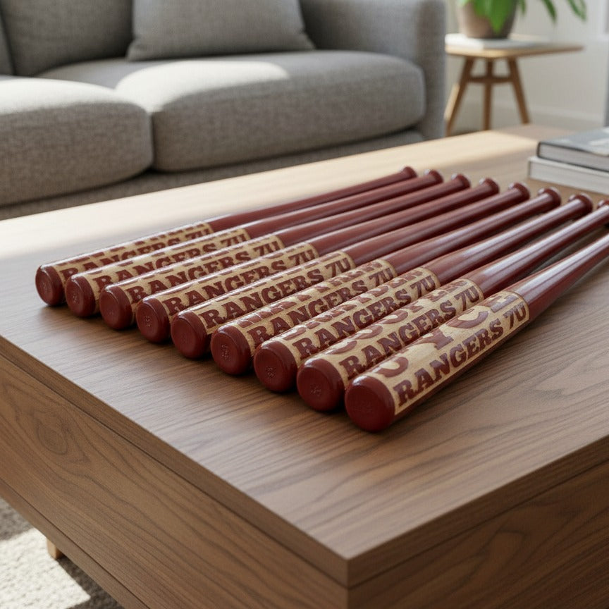Set of burgundy baseball bats with sample engraving reading "RANGERS" and "70" displayed on wooden table