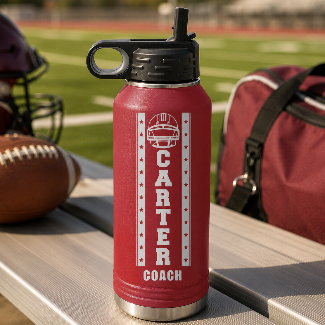 Red insulated water bottle with black spout featuring engraved "CARTER COACH" text and football helmet design with stars on a stadium background.