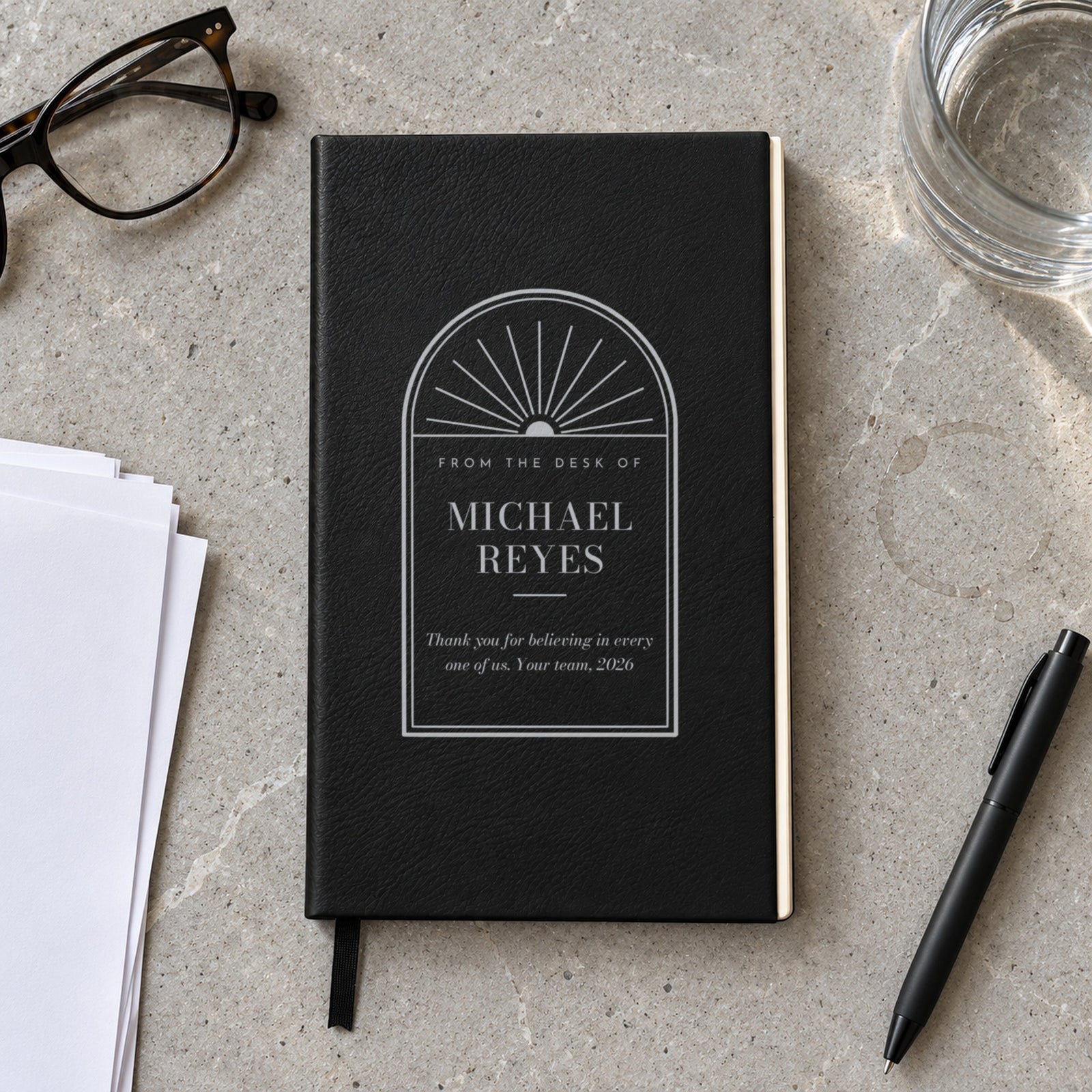 Black boss gift journal engraved in silver From the Desk of Michael Reyes with a thank-you message from the team, on a conference table