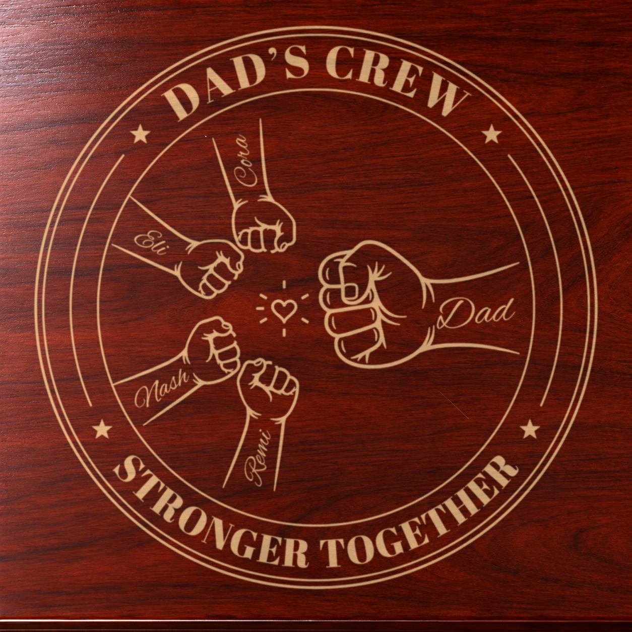 Close-up of the engraved Dad's Crew badge on cherry wood: four kids' fists with their names bumping Dad's fist around a heart, Stronger Together below