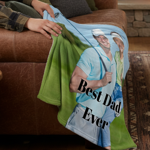 Personalized fleece blanket with "Best Dad Ever" text and sample photo of two men on brown leather couch, green fabric detail visible.