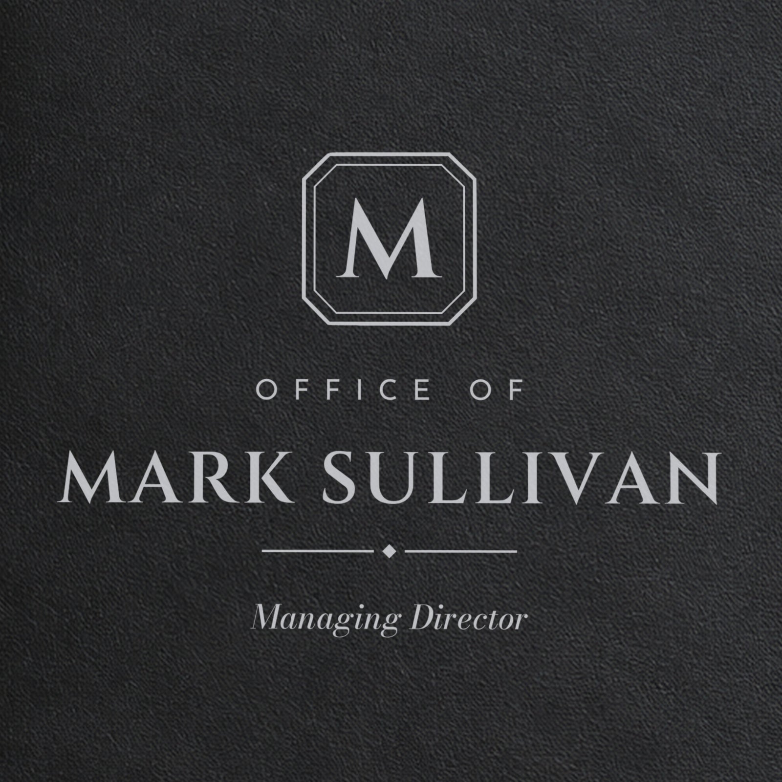 Close-up of the silver laser engraving on the black padfolio: M monogram plate, Office of, Mark Sullivan and Managing Director in italic