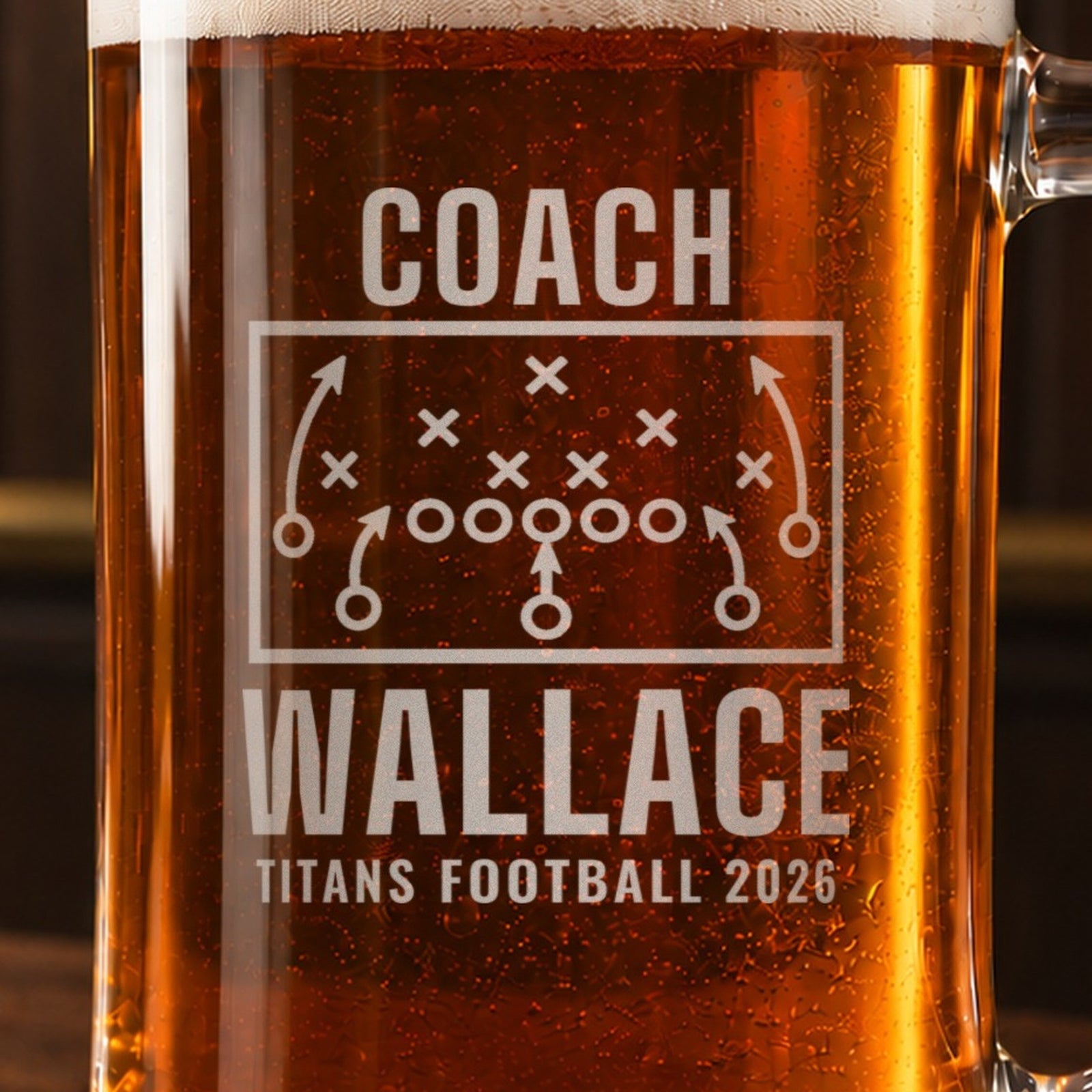 Close-up of the frosted engraving on the football coach playbook beer stein, a football play diagram with X's, O's and routes: Coach, Wallace, Titans Football 2026