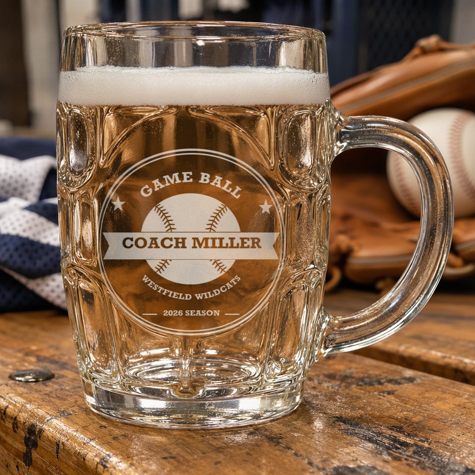 Personalized baseball coach beer stein on a locker room bench beside a baseball glove and ball, frosted engraving reading Game Ball, Coach Miller and Westfield Wildcats