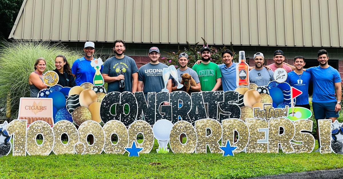 The Groovy Gifts team outside the Monroe, Connecticut workshop celebrating 100,000 orders with a Congrats 100,000 Orders yard sign