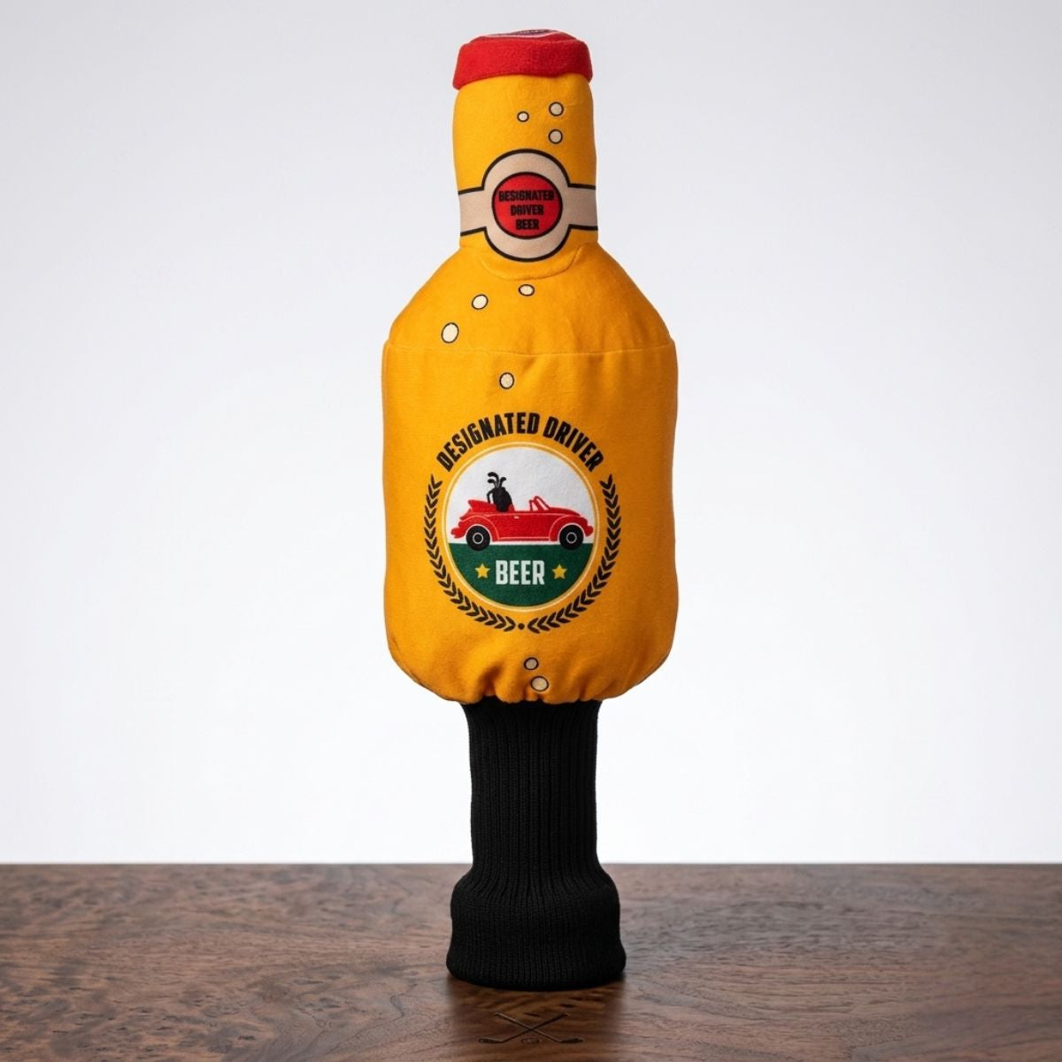Yellow beer bottle-shaped golf club headcover with red cap, featuring "Designated Driver Beer" graphics and a red car illustration on the front.