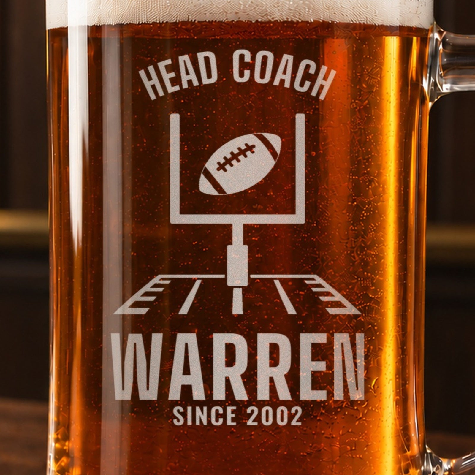 Close-up of the frosted engraving on the head coach football beer stein, football goalposts with a ball sailing through: Head Coach, Warren, Since 2002