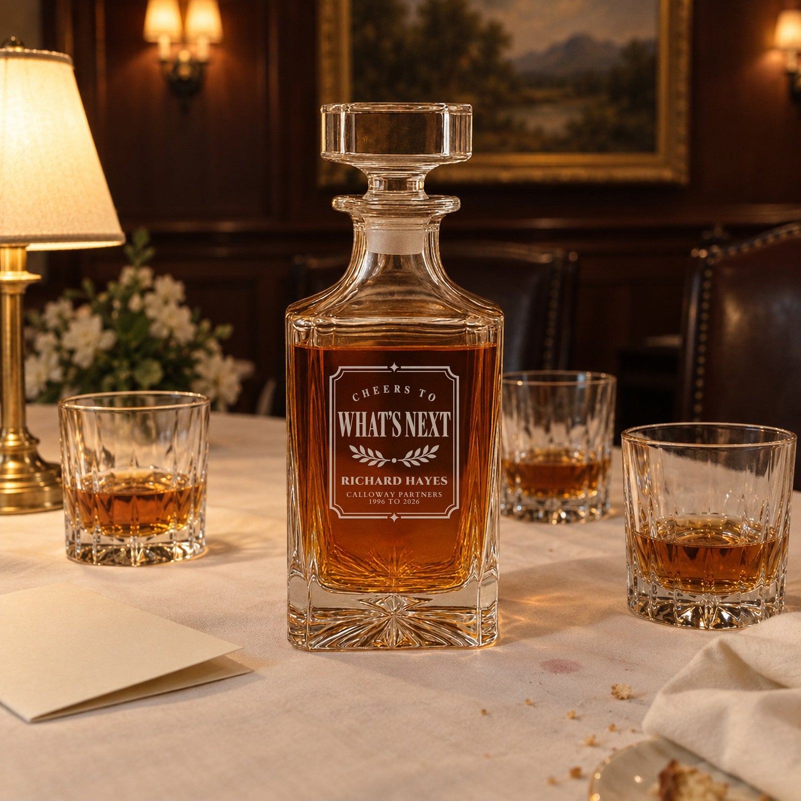 Engraved Cheers to What's Next decanter at a farewell dinner with rocks glasses of bourbon, a leaving present for a boss named Richard Hayes