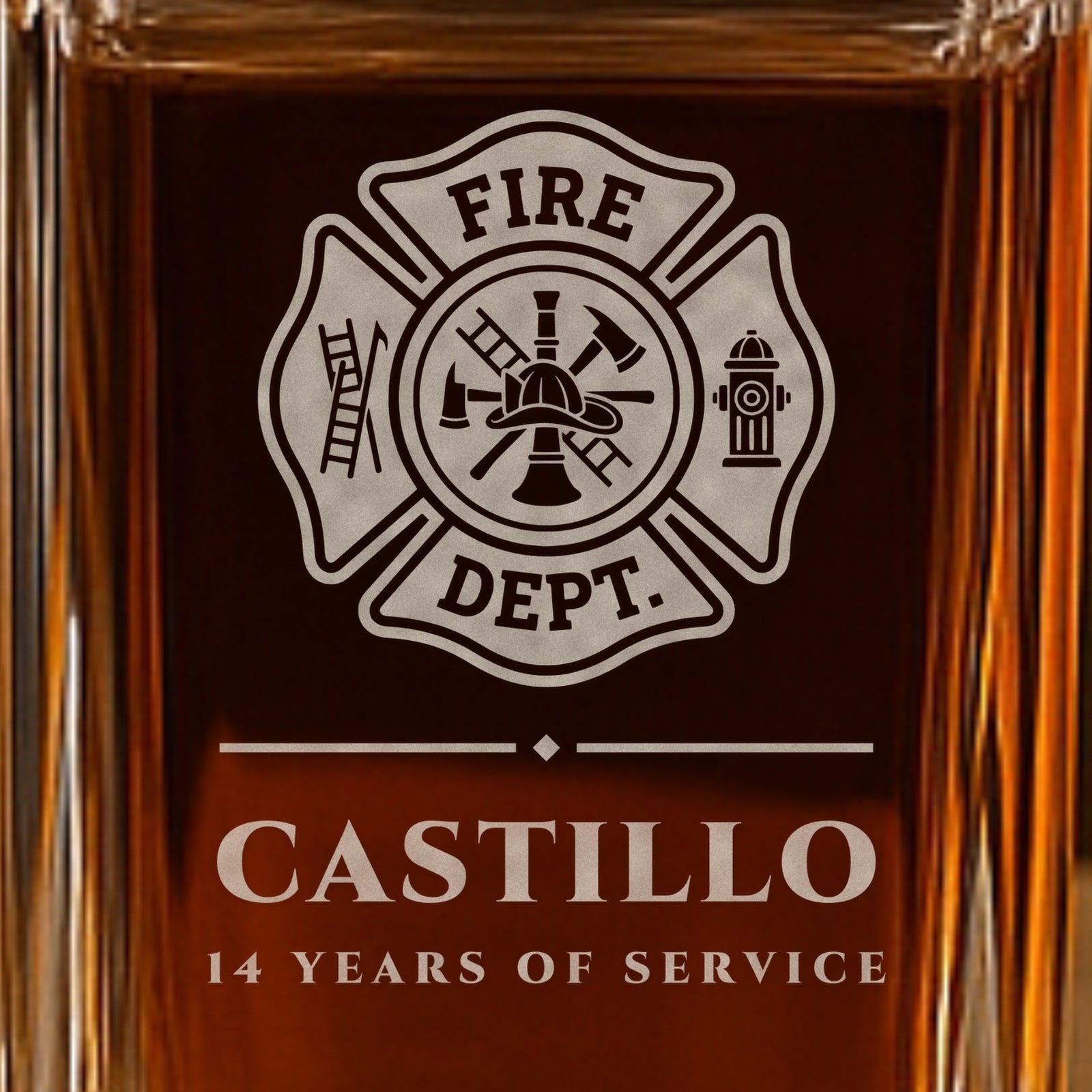 Close-up of the frosted Maltese cross engraving on a whiskey decanter with the name Castillo and 14 Years of Service, a gift for firefighters