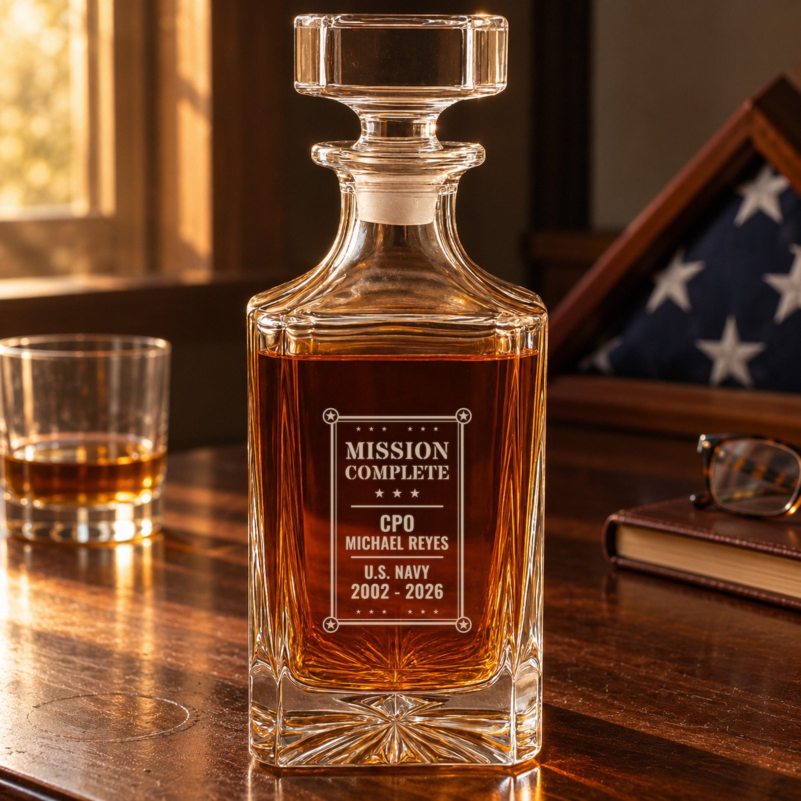 Personalized retirement decanter engraved Mission Complete, CPO Michael Reyes, U.S. Navy, on a desk beside a folded flag case