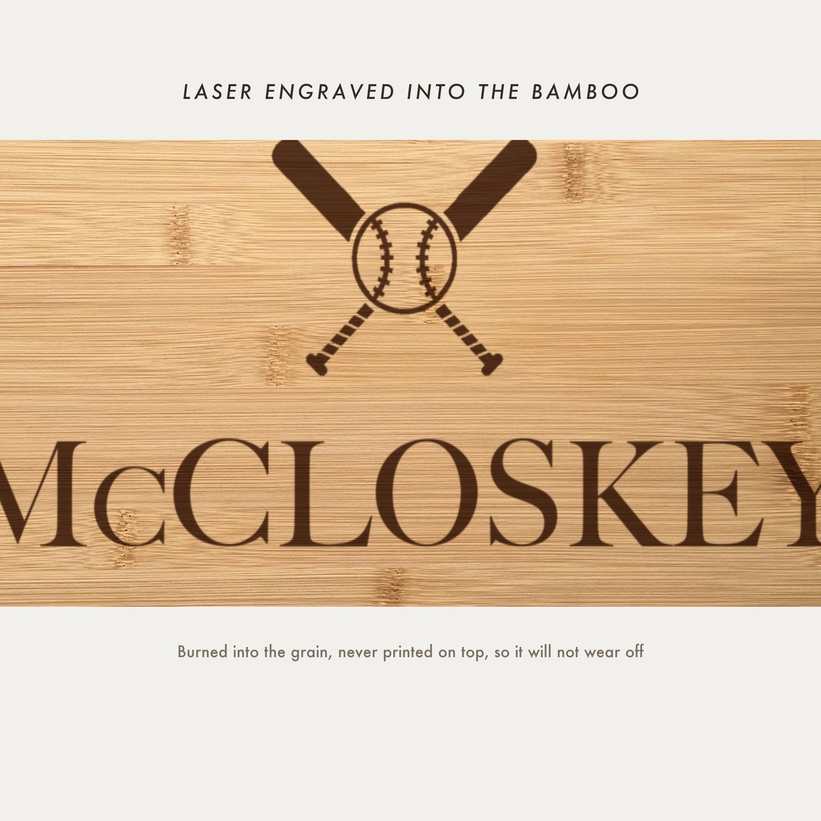 Close view of the crossed baseball bats and stitched ball laser engraved into the bamboo grain above the name in a high contrast serif.