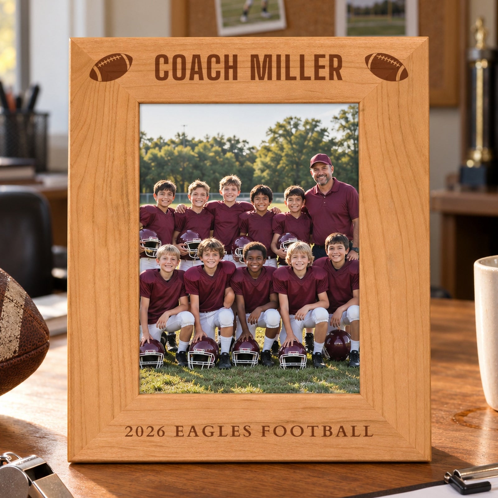 Personalized coach picture frame in red alder engraved Coach Miller with footballs and 2026 Eagles Football, holding a youth football team photo on a desk