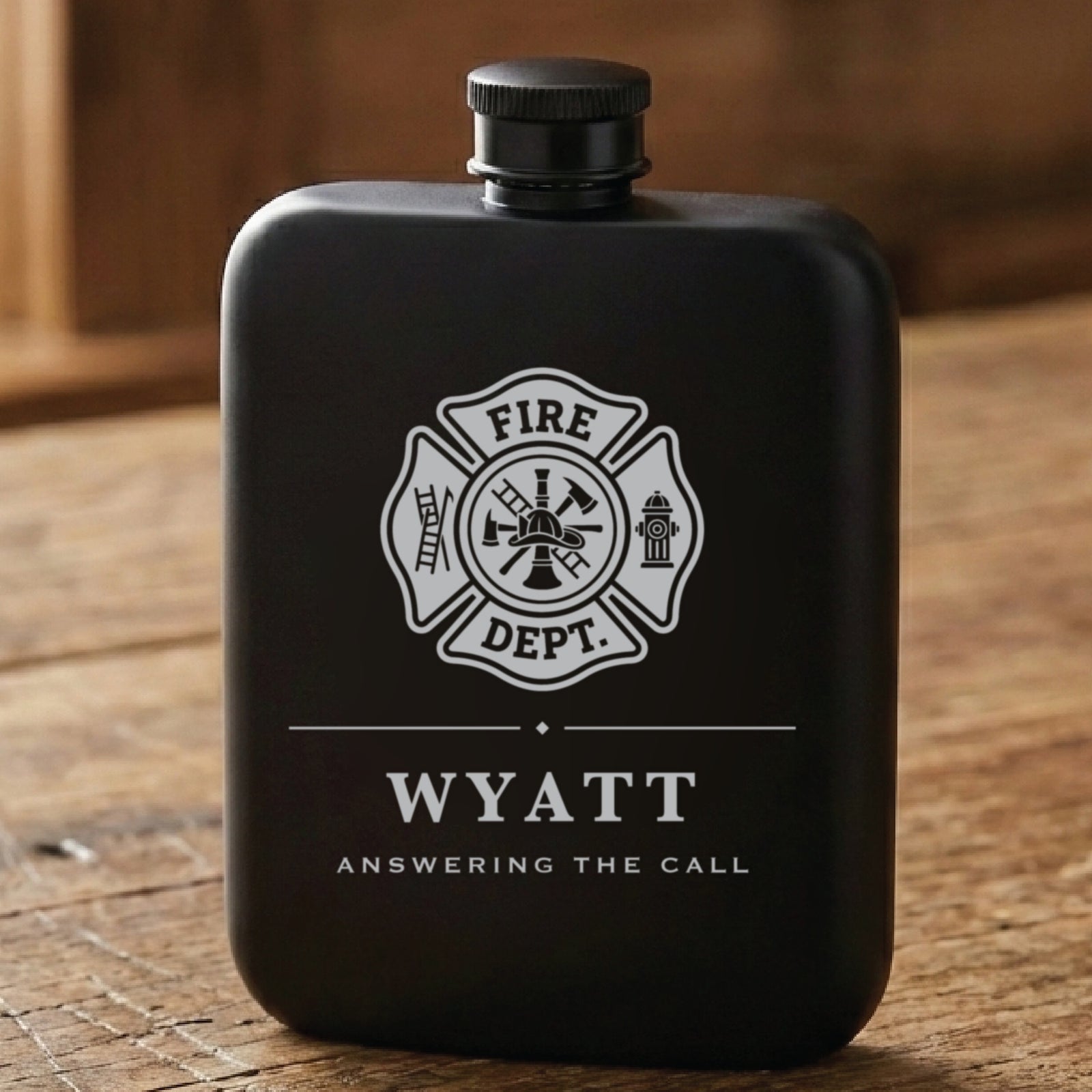 Matte black personalized firefighter flask laser engraved with the Fire Dept Maltese cross, the name Wyatt and Answering The Call.