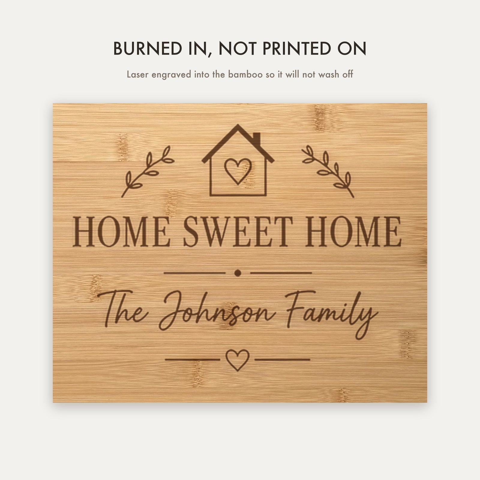 Close view of the laser engraving burned into the bamboo grain showing the Home Sweet Home crest and the personalized family name in script.