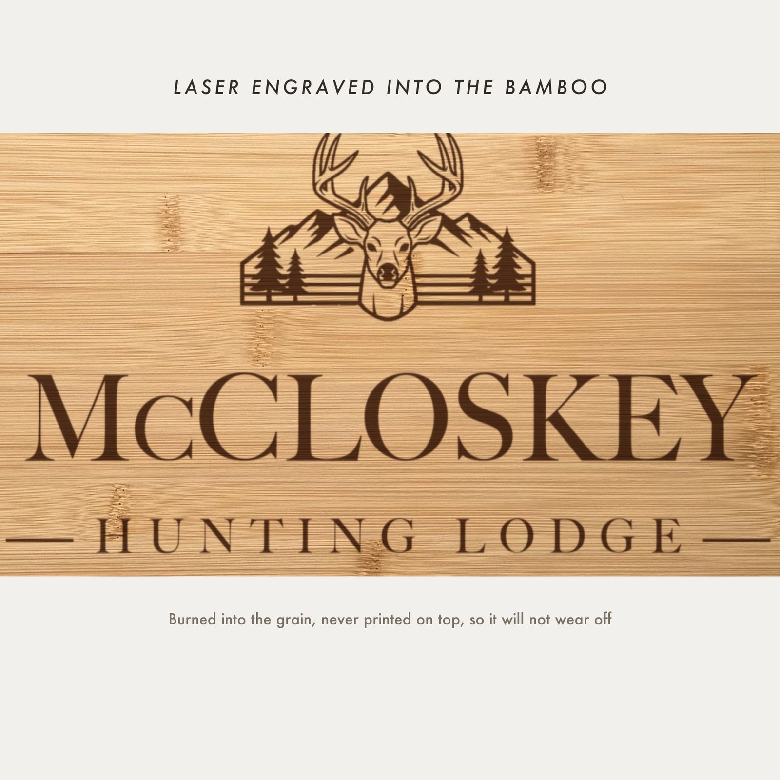 Close view of the buck with antlers, mountain range and pine trees laser engraved into the bamboo grain above the family name.