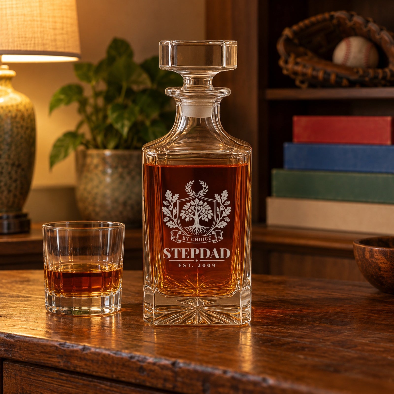 Personalized stepdad whiskey decanter engraved Stepdad, Est. 2009 under an oak tree crest with a By Choice ribbon, on a sideboard in a family den
