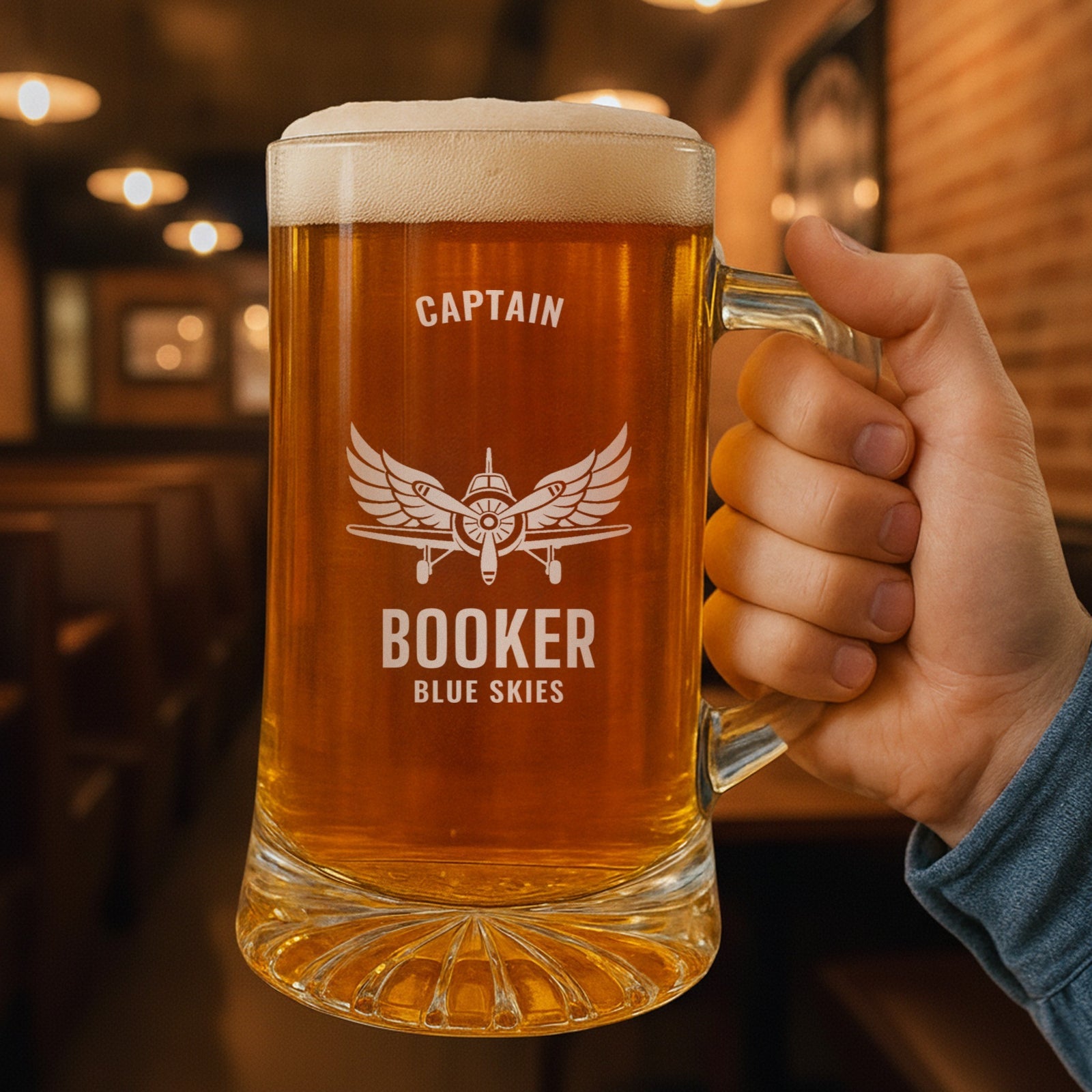 Hand holding the 25 oz personalized pilot beer stein in a pub, engraved with a vintage propeller airplane and spread wings: Captain, Booker, Blue Skies