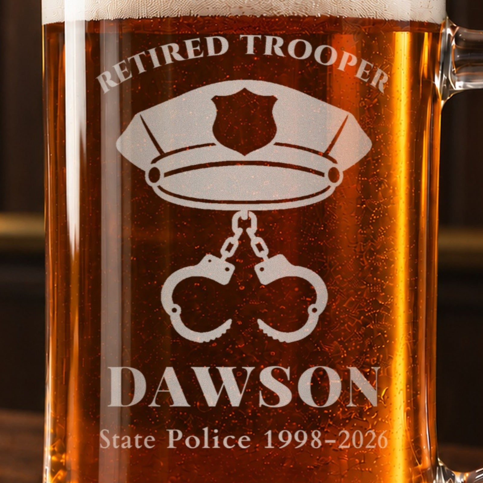 Close-up of the frosted patrol cap and handcuffs engraving on a retired trooper beer mug reading DAWSON and State Police 1998-2026