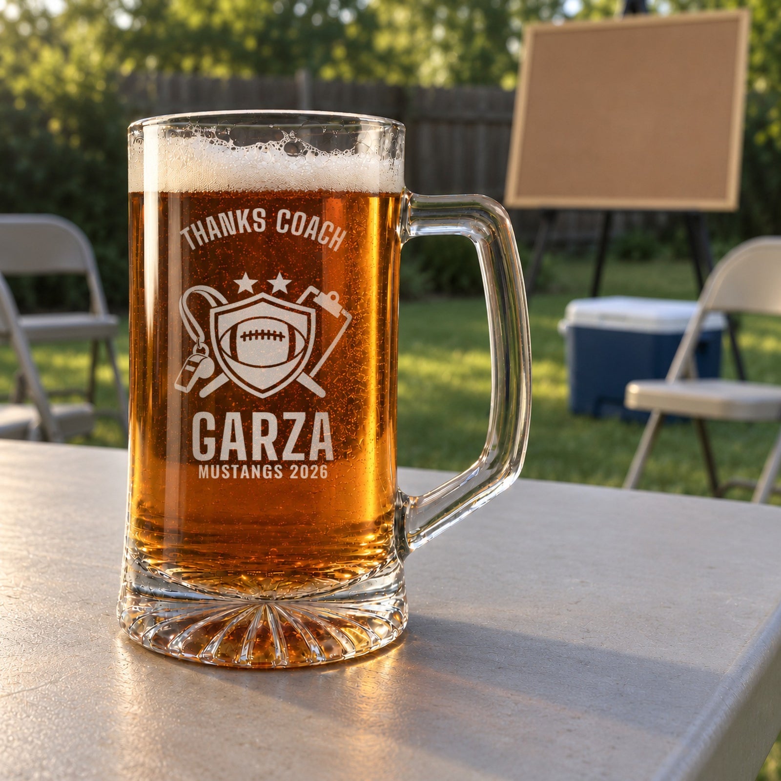 Personalized thanks coach football beer stein in a real setting, engraved with a shield with a football, a whistle and a clipboard: Thanks Coach, Garza, Mustangs 2026