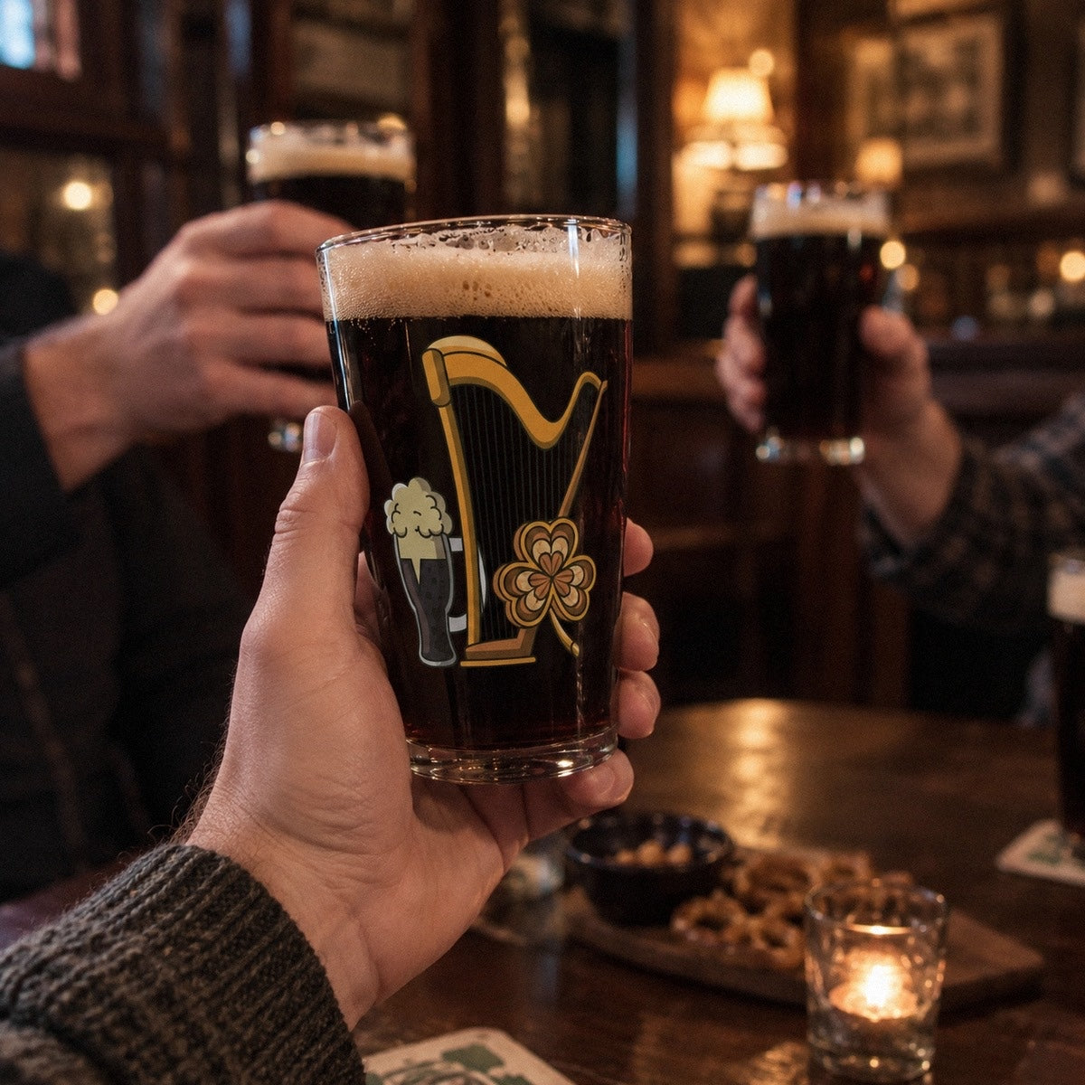 A man in a wool sweater raises his Irish harp pint of stout in a cozy pub, the golden harp, pint and shamrock print facing the camera