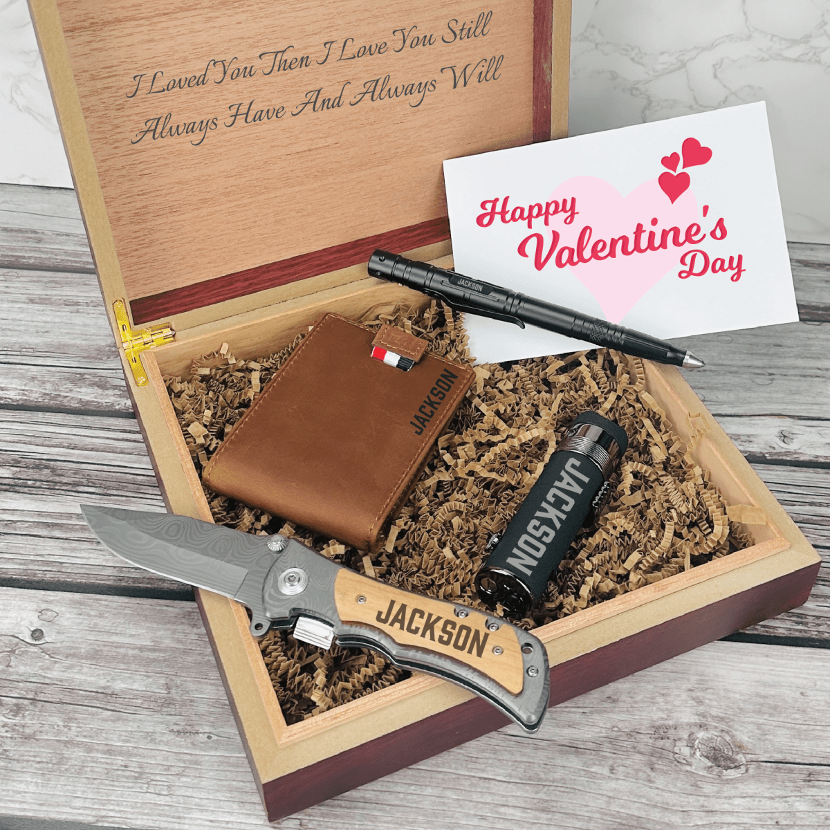 Personalized Valentine’s Day gift set for men featuring a tactical pen, triple torch lighter, wallet, titanium-coated knife, and engraved wooden box with custom name and message.