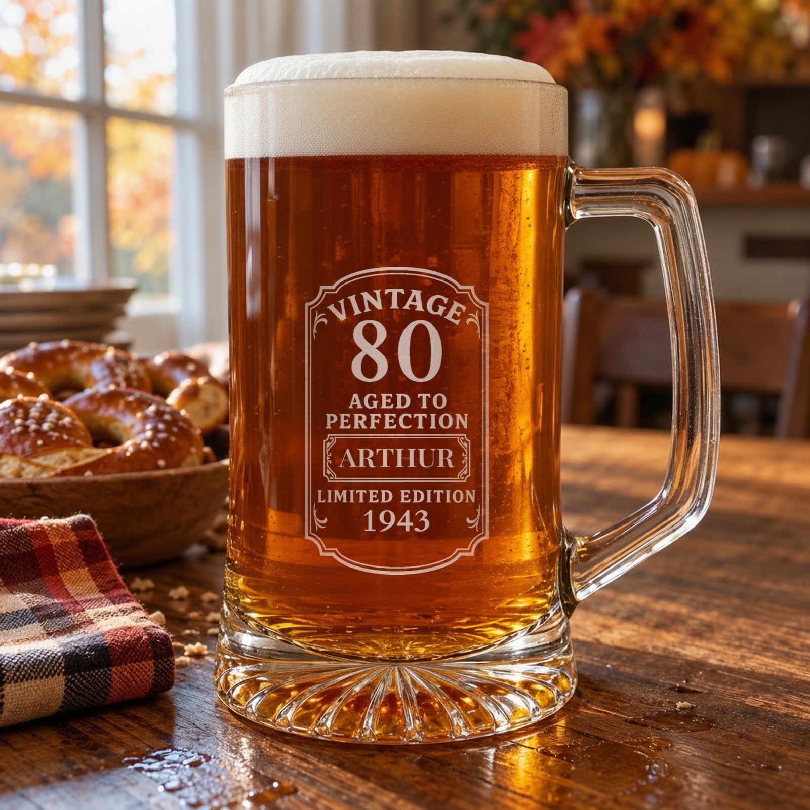 Engraved 80th birthday beer stein of amber lager on an autumn kitchen table, the Vintage 80 label personalized for Arthur, born 1943