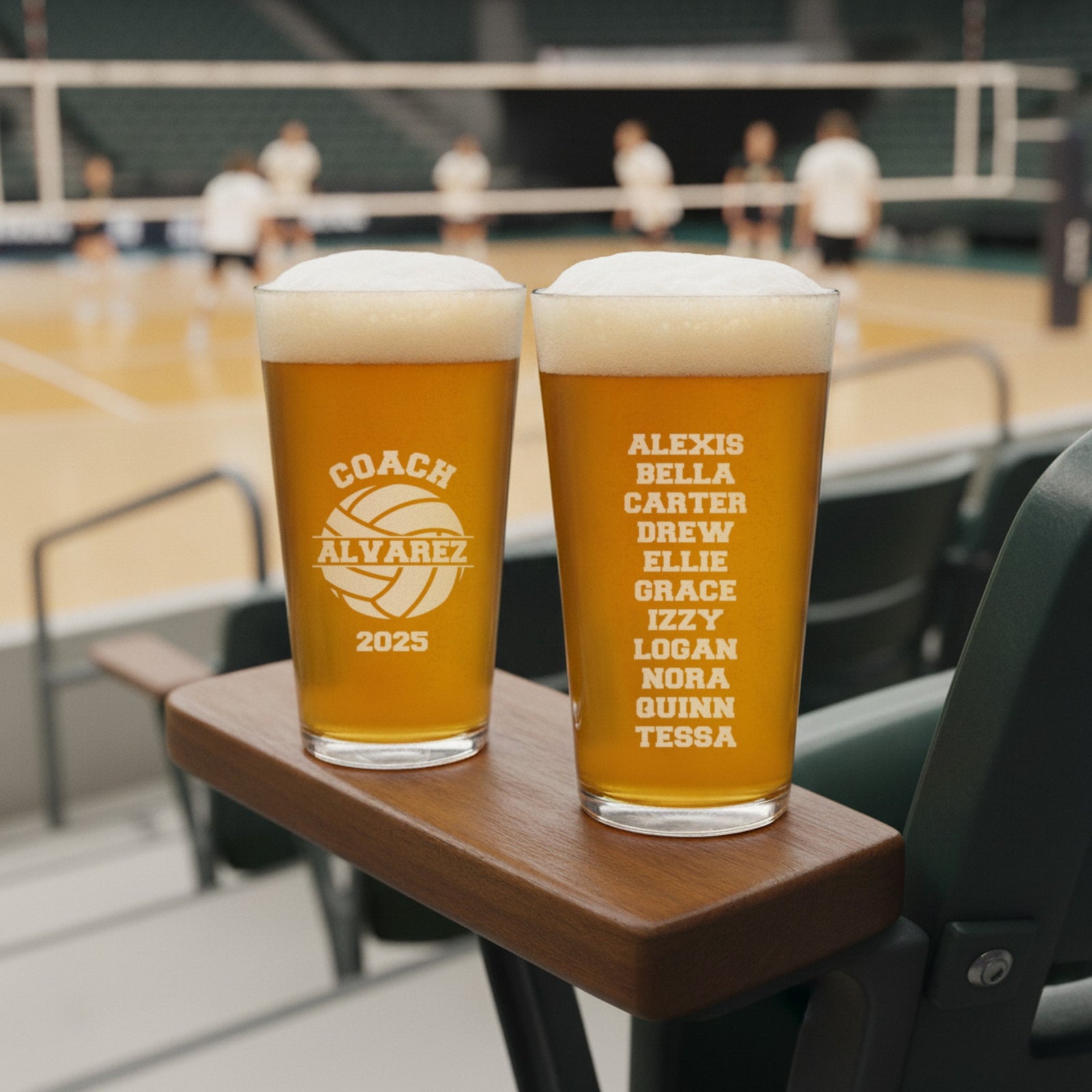 Two engraved volleyball coach pint glasses on an arena seat armrest, Coach Alvarez 2025 on the front and the team roster on the back