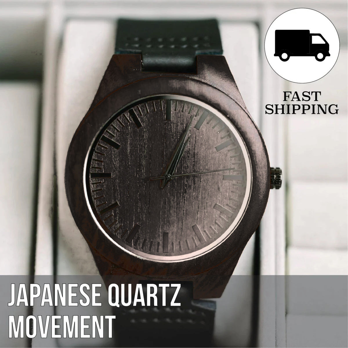 Close view of the dark ebony sandalwood watch in a white display case, showing the wood grain dial, the minute markers, the crown and the black leather strap