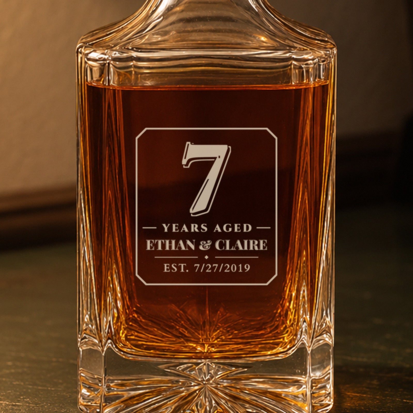 Close-up of the frosted engraving: a bold 7, Years Aged, Ethan & Claire, est. 7/27/2019, on a personalized 7th anniversary decanter